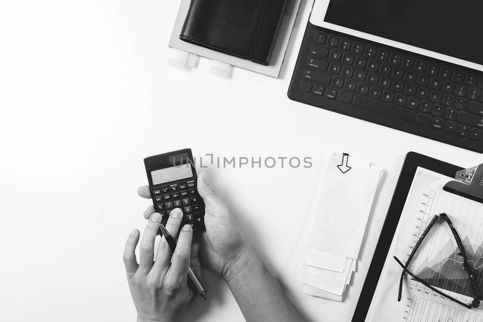 top view of businessman hand working with finances about cost and calculator and latop with mobile phone on withe desk in modern office,black with white