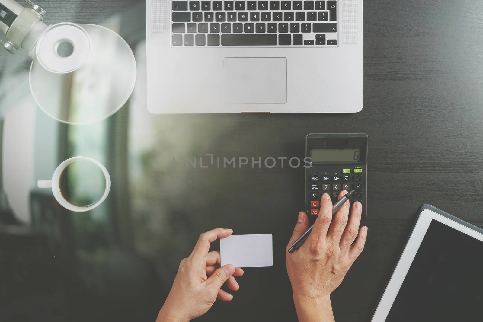 Internet shopping concept.Top view of hands working with calculator and laptop and credit card and tablet computer on dark wooden table background