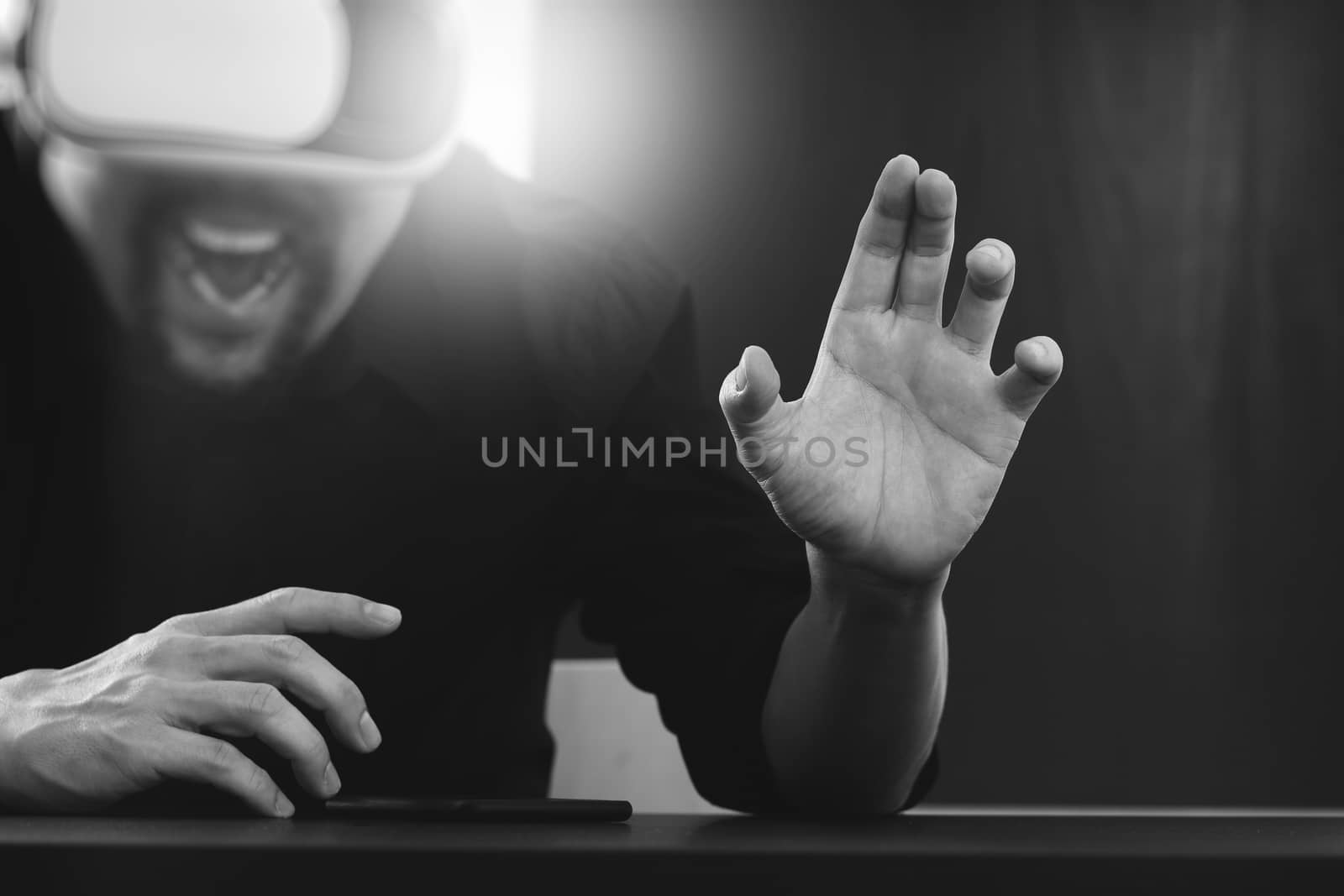 businessman wearing virtual reality goggles in modern office with mobile phone using with VR headset,black and white 