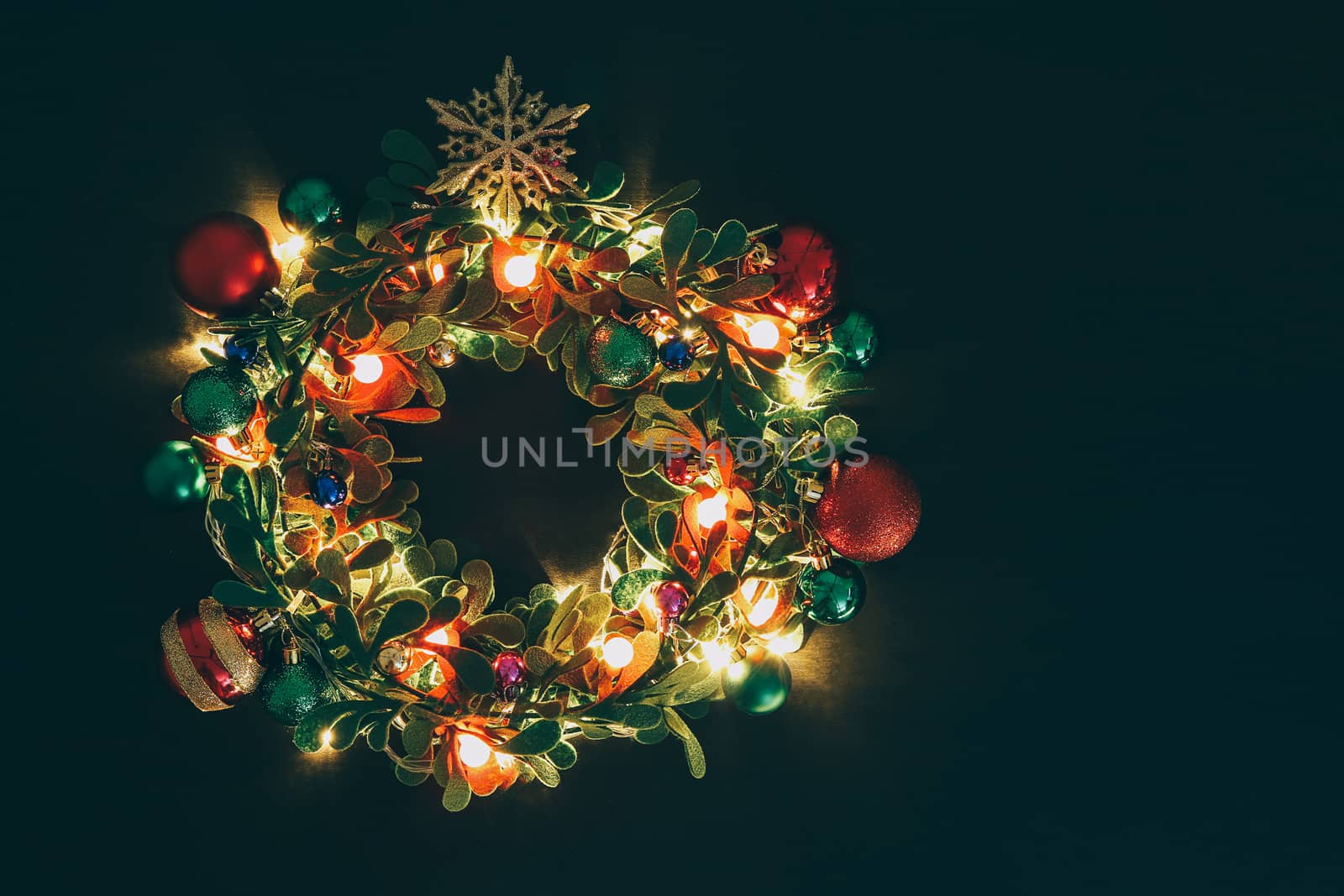 Greeting Season concept.Christmas wreath with decorative light on dark wood background