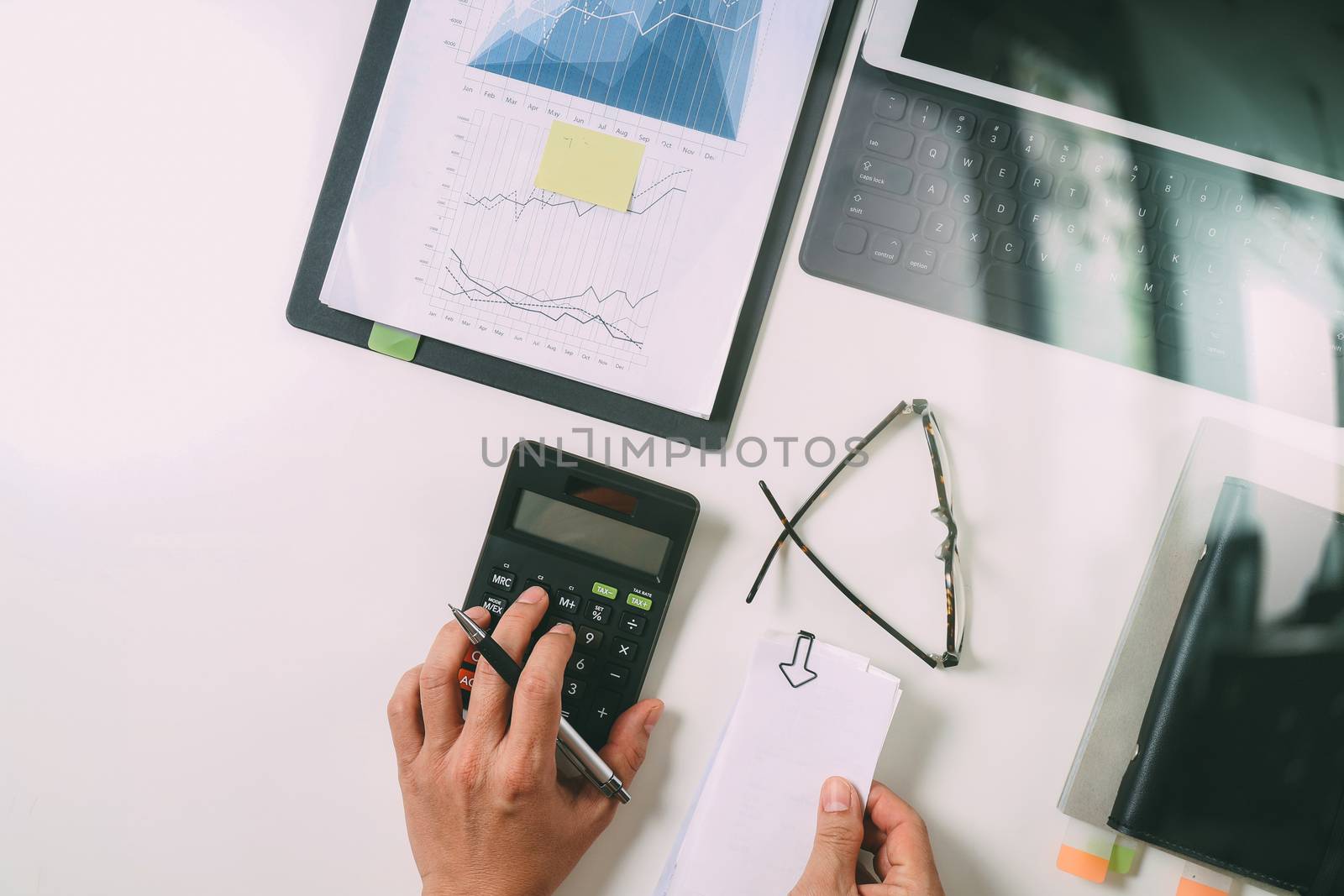 top view of businessman hand working with finances about cost and calculator and latop with mobile phone on withe desk in modern office 