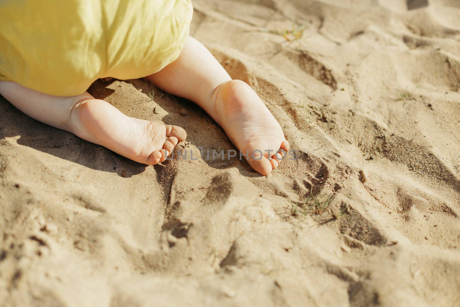 A close-up view of the heel of a child who is crawling on the sand. View from above