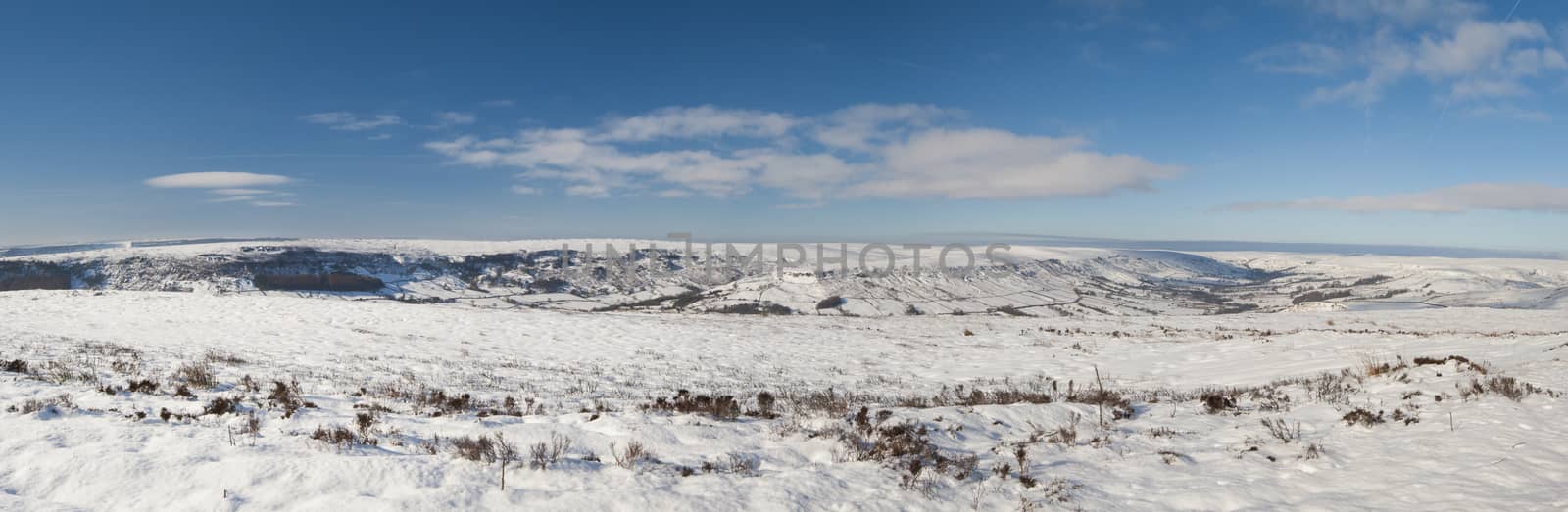 Panoramic view over a snowy winter english countryside rural landscape with fields and meadows
