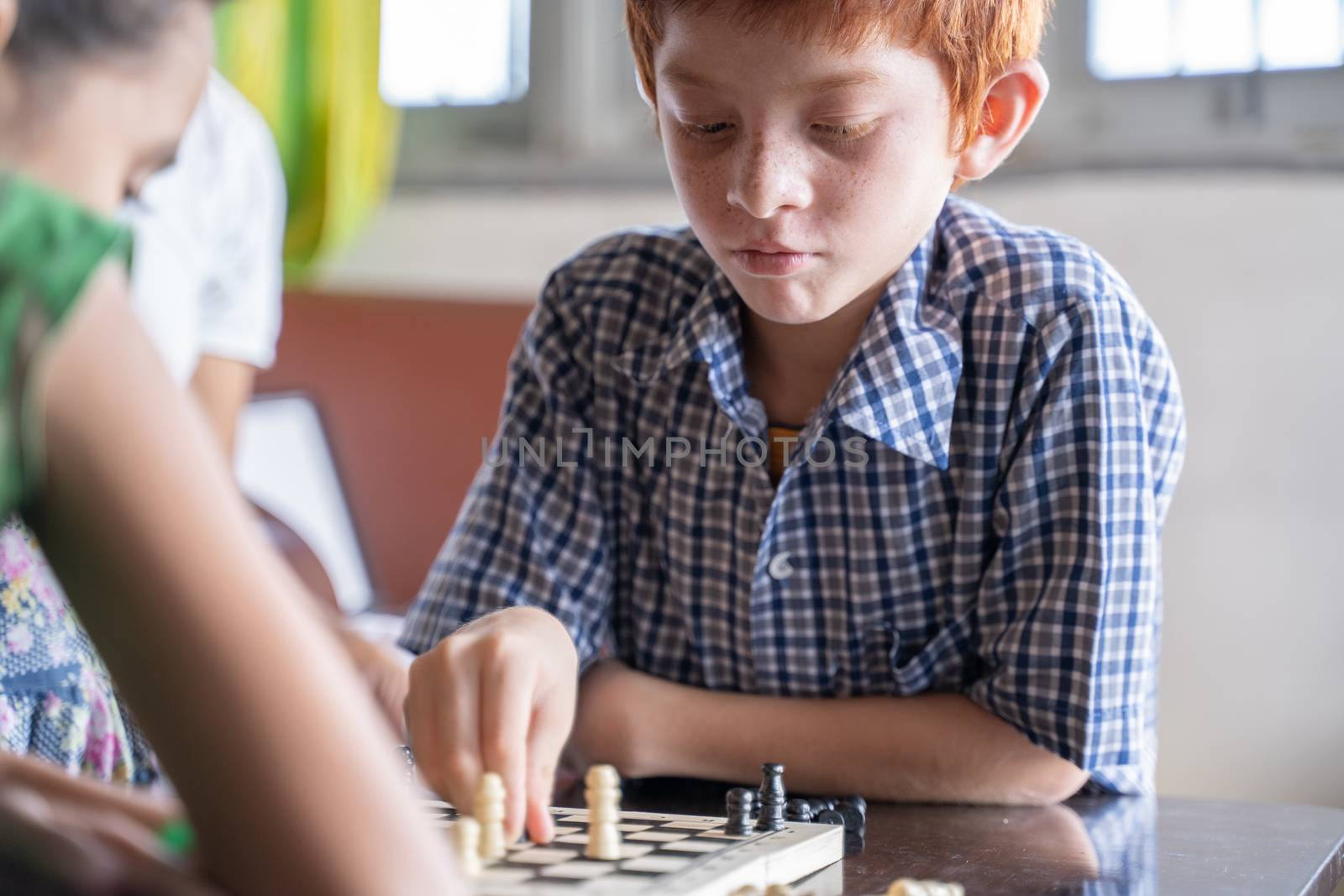 Serious chess player kid thinking and moving coin at home - Concept of kid concentration of game during Early development, home educational games for children.