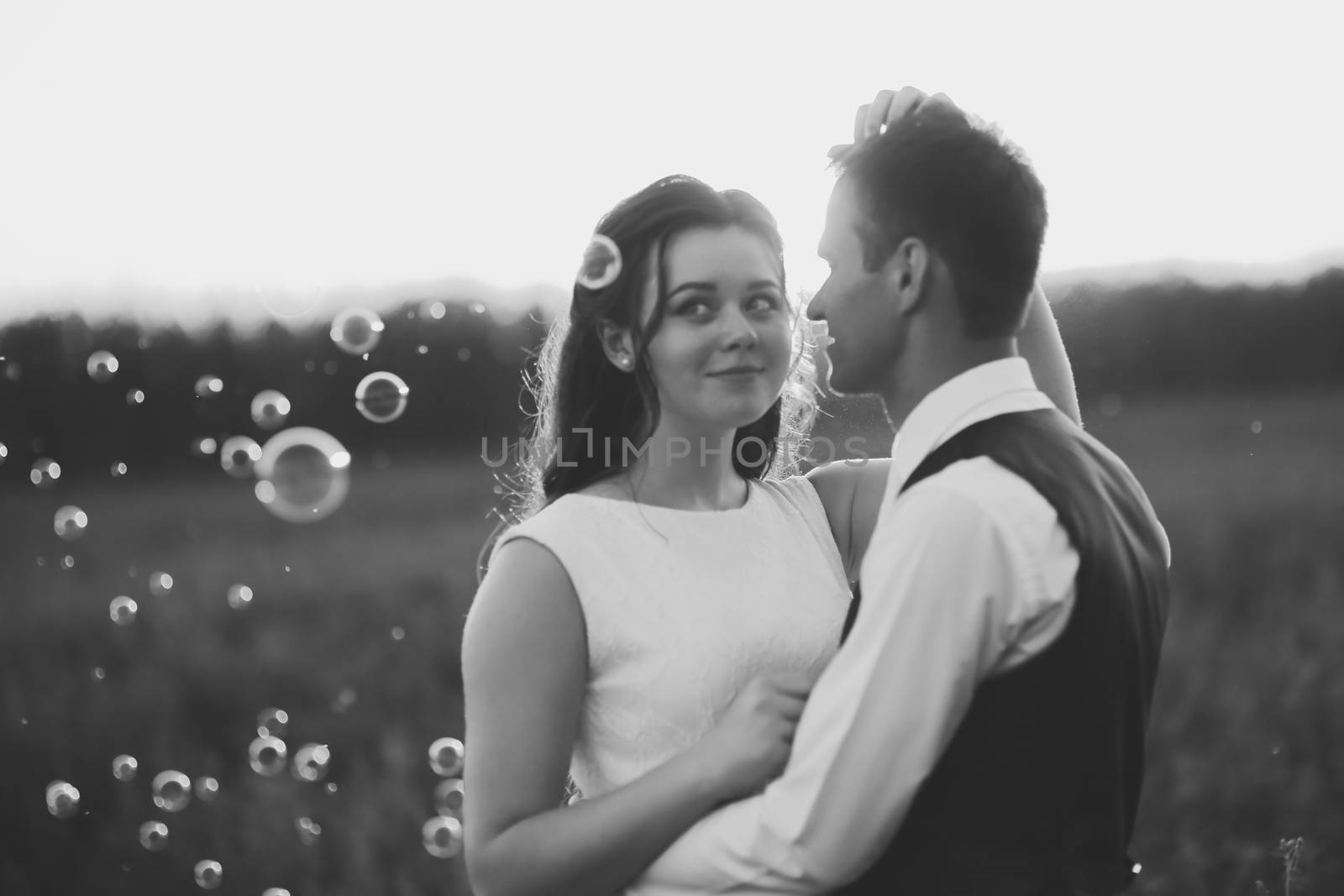 Happy bride and groom hug each other in the park at sunset. Soap bubbles. Wedding. Happy love concept. High quality photo