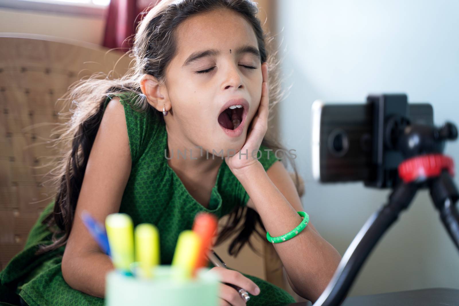 Sleepy boredom kid yawning during online class infront of mobilephone - concept of tired or bored child during homeschooling, online education at home due to covid-19 or coronavirus crisis