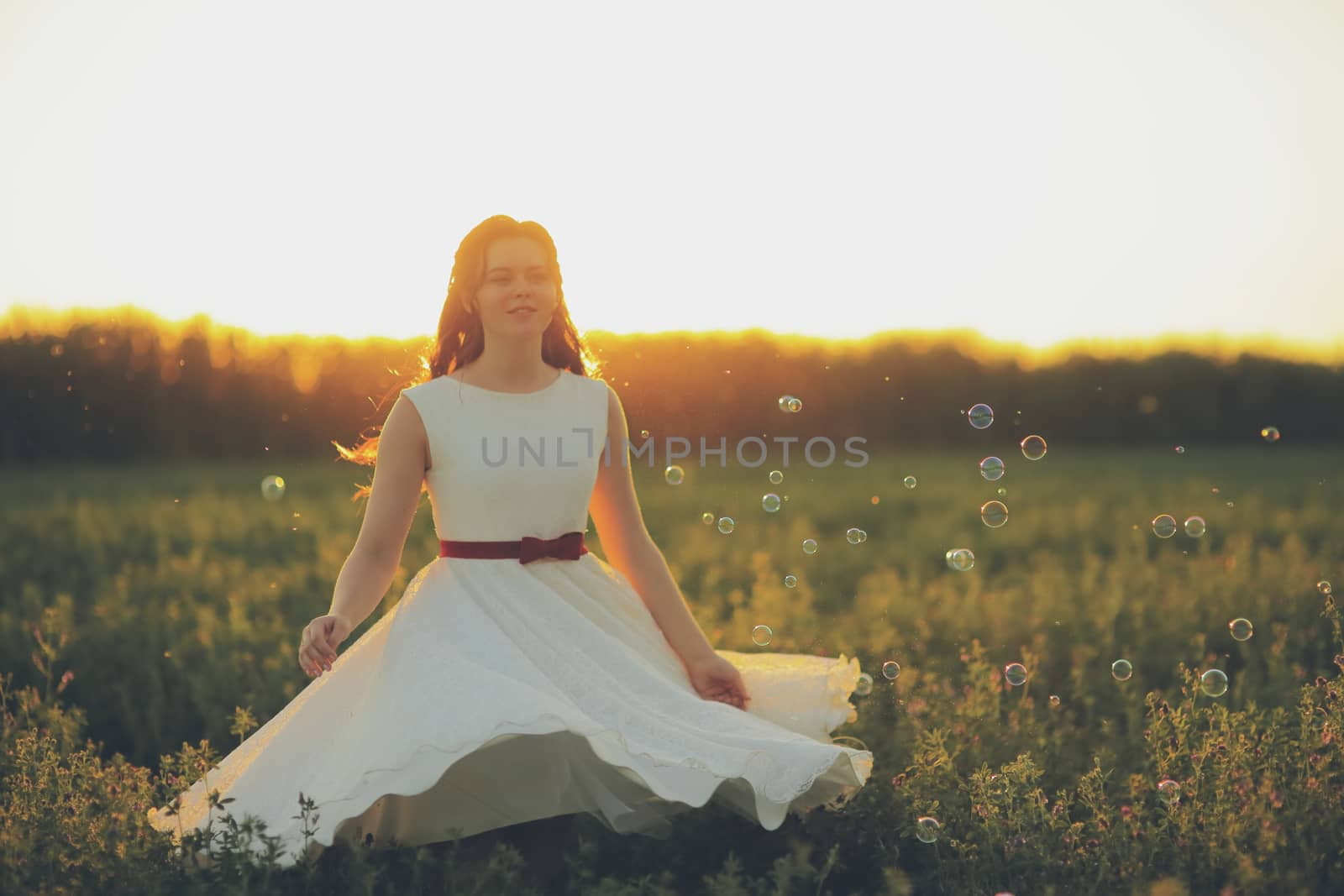 Beautiful girl dancing in a park in the sunset light. Soap bubbles. Happiness concept. High quality photo