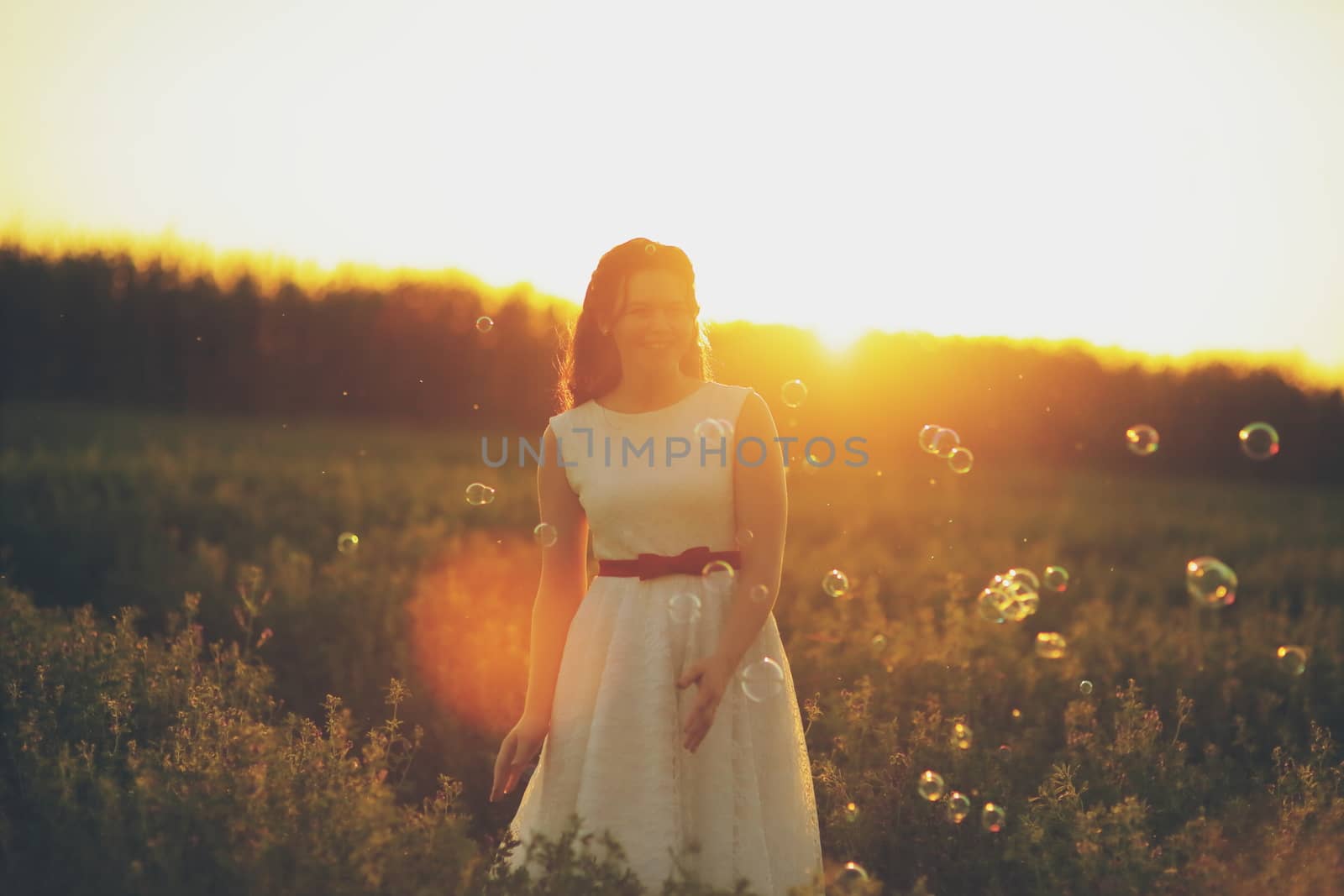 Beautiful girl dancing in a park in the sunset light. Soap bubbles. Happiness concept. by selinsmo