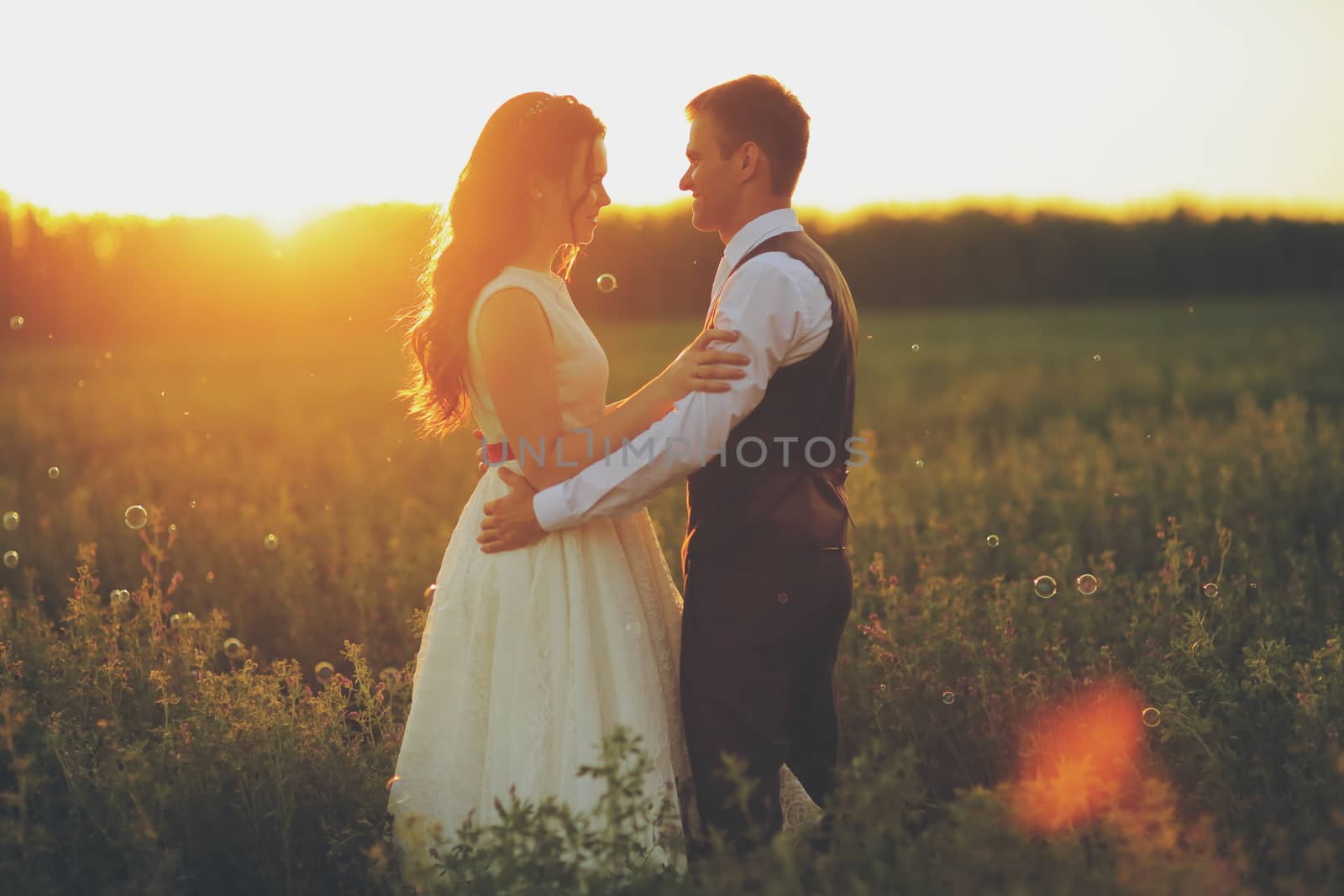 Happy bride and groom hug each other in the park at sunset. Wedding. Happy love concept. by selinsmo