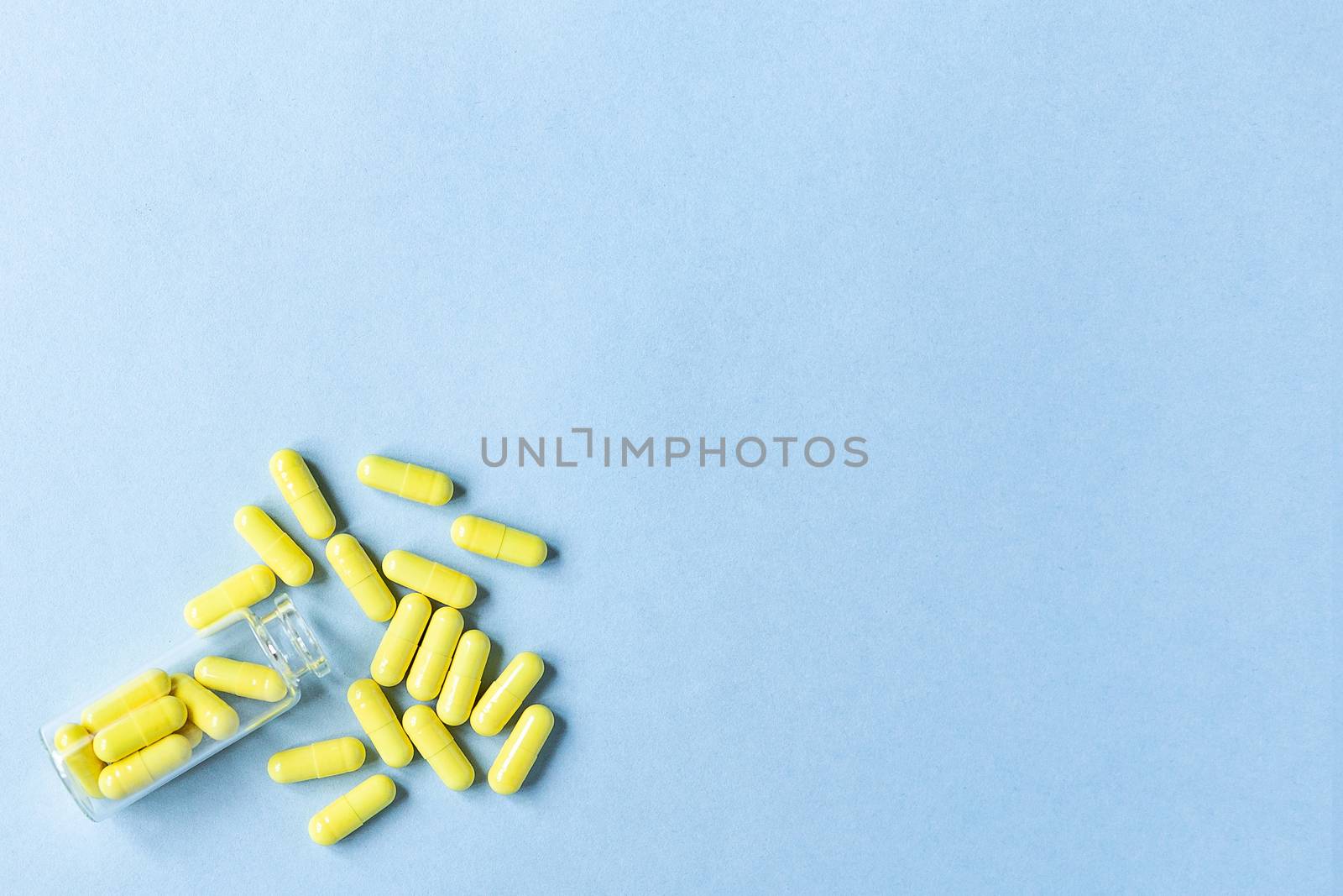 Yellow capsules are poured out of a bottle on a blue background. Omega-3 vitamins. food Supplement. space for text. copy space. blurred background. Selective focus. concept of medicine. Free space.