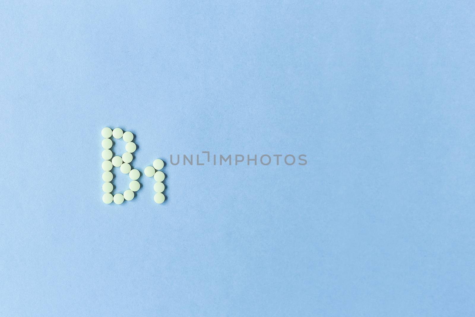 Yellow tablets forming B1 on a blue background. Vitamin complex. Concept, health care, healthy nutrition. Medicine. Healthy lifestyle. Food additive. copy space. Soft focus. blurry background. Good by Pirlik