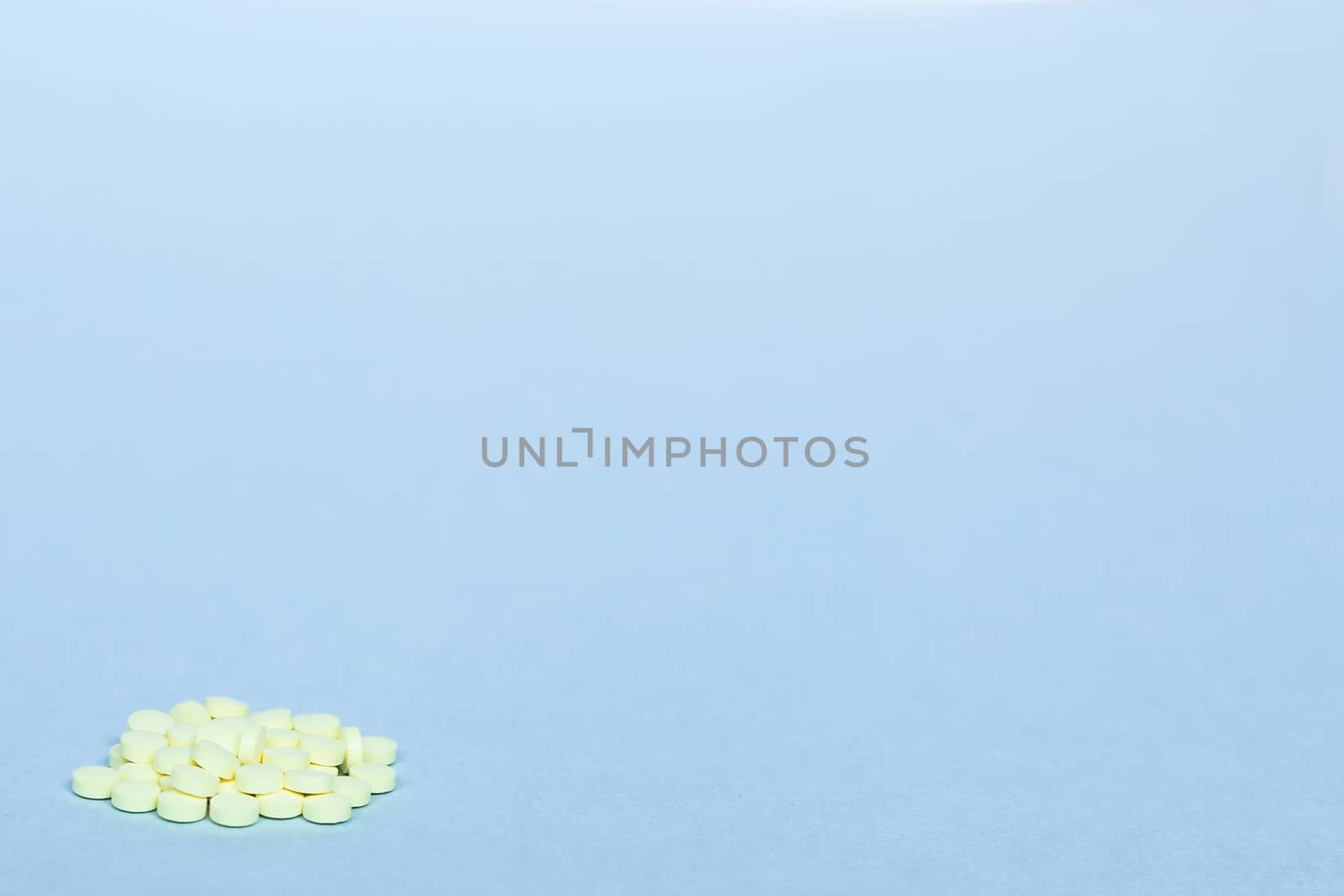 handful of yellow pills on a blue background. concept of healthcare, medicine, vitamins. background, free space, copy space. blurry background. cluster of yellow pills on a blue background. soft focus by Pirlik