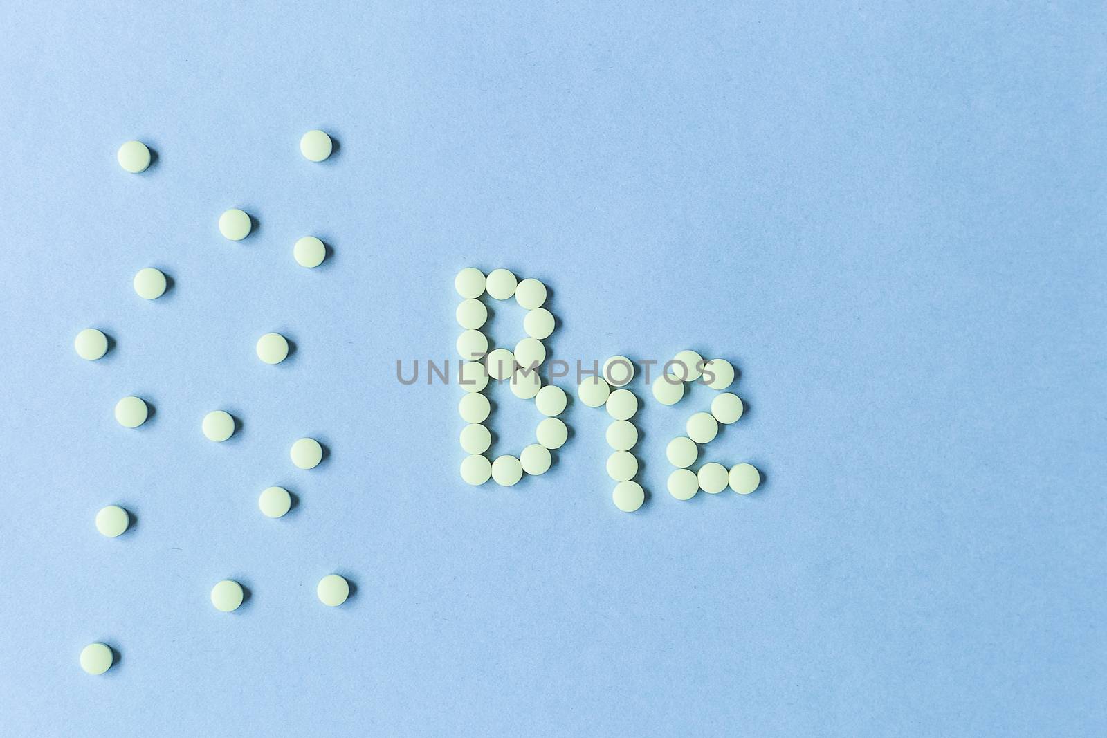 Yellow pills forming shape to B12 alphabet on blue background. Vitamin complex. Concept, health care, healthy nutrition. Healthy lifestyle. Food additive. copy space. Soft focus. blurry background. by Pirlik