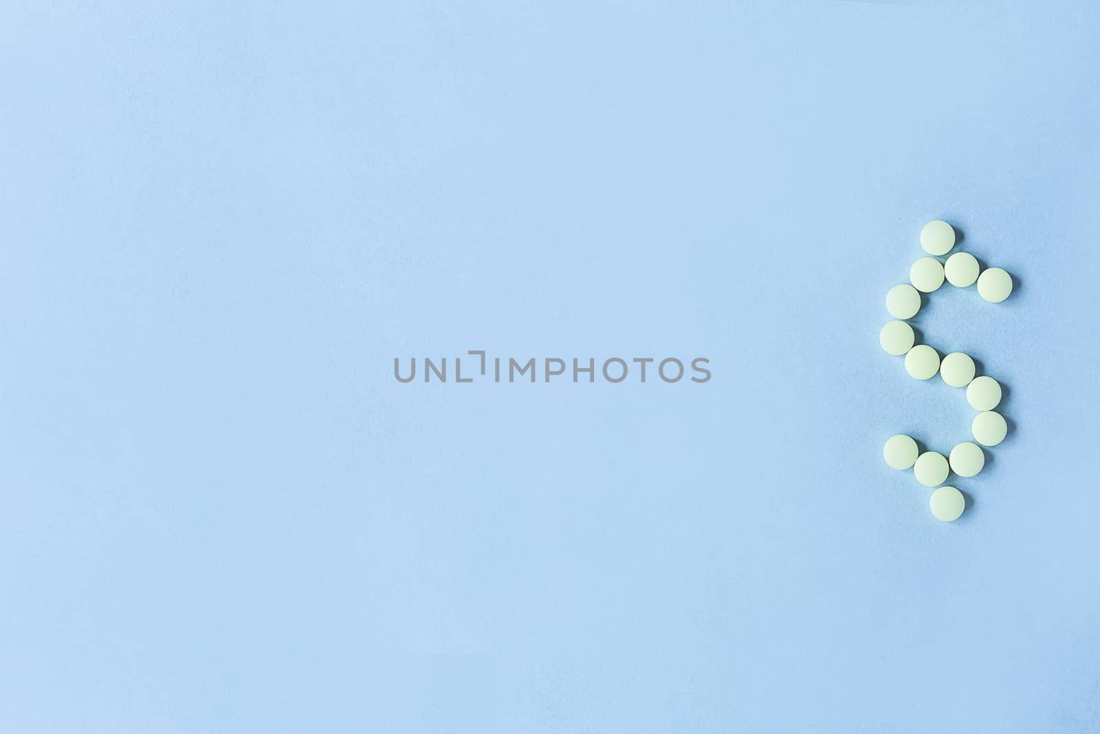 tablets in the form of a dollar sign on a blue background. Concept of a dollar sign made with vitamin tablets on a blue background.banner. copy space. soft focus, blurry background. space for text.