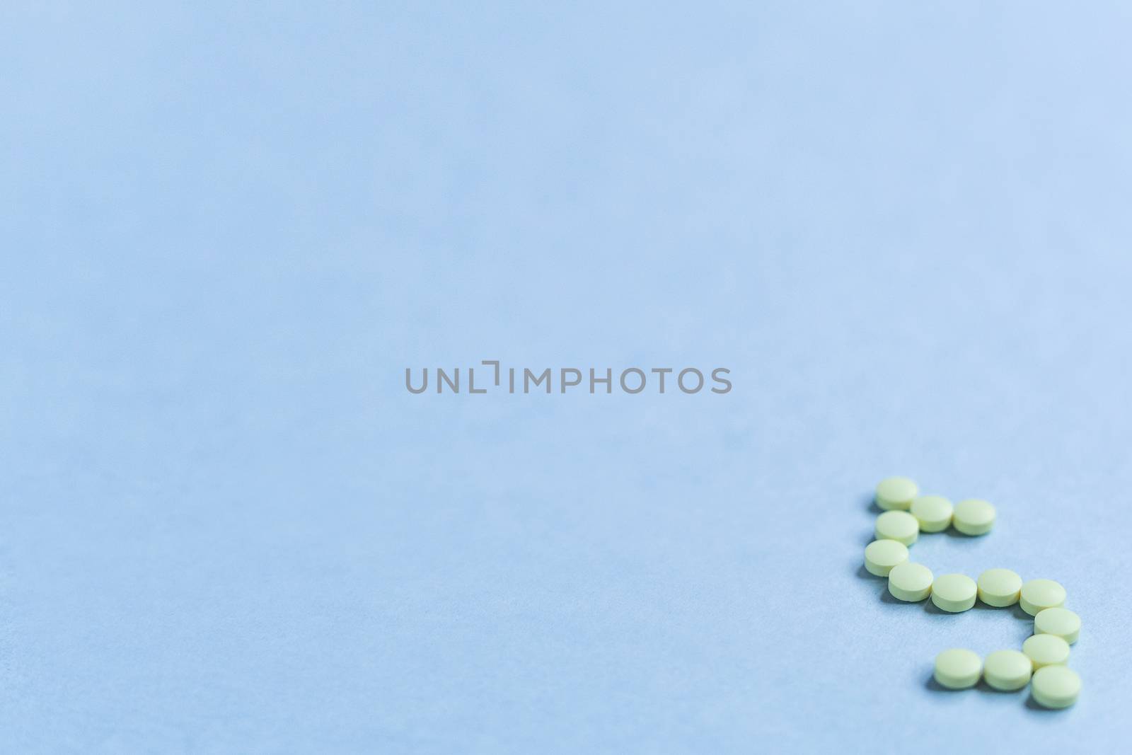 tablets in the form of a dollar sign on a blue background. Concept of a dollar sign made with vitamin tablets on a blue background. banner. space for text. copy space. soft focus, blurry background by Pirlik