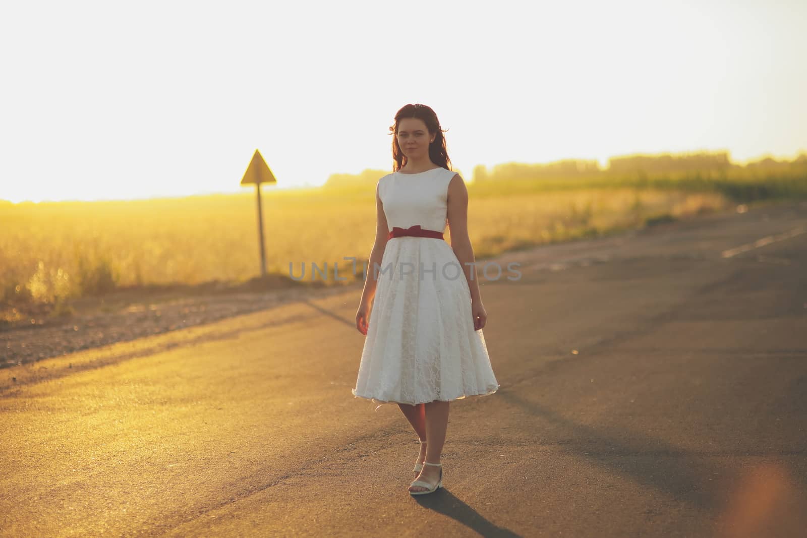 Beautiful girl walks along the road in sunset light. Happiness concept. High quality photo