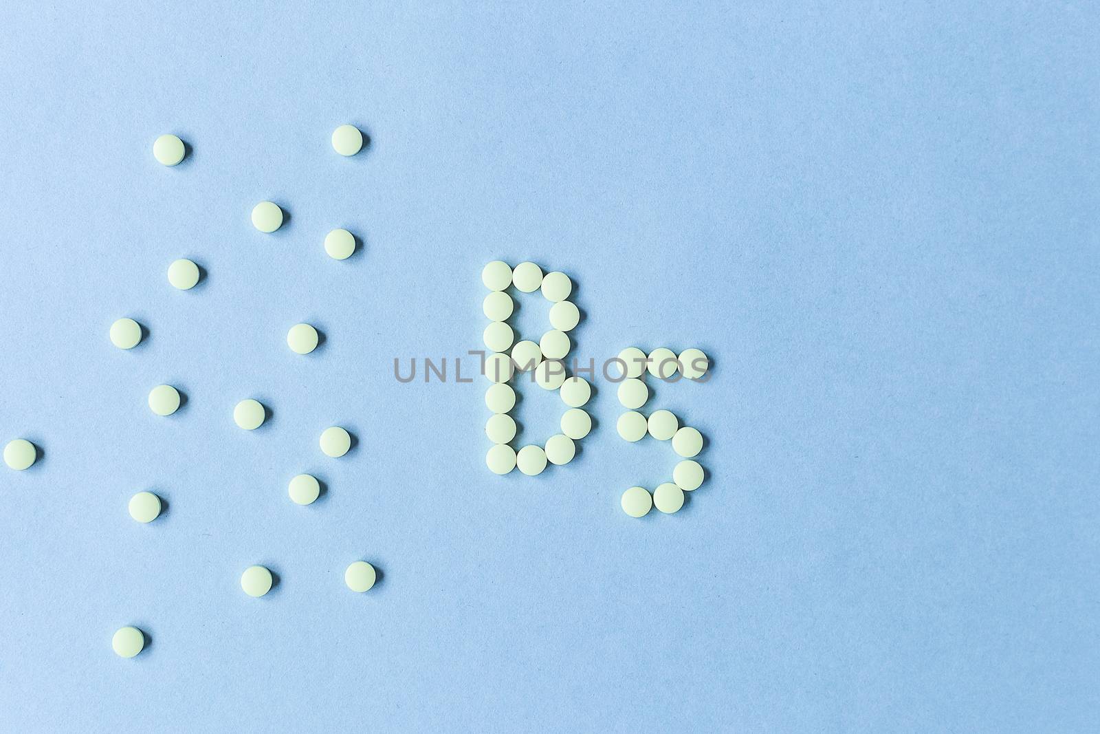 Yellow tablets forming B5 on a blue background. Vitamin complex. Concept, health care, healthy nutrition. Medicine. Healthy lifestyle. Food additive. copy space. Soft focus. blurry background. Banner. by Pirlik