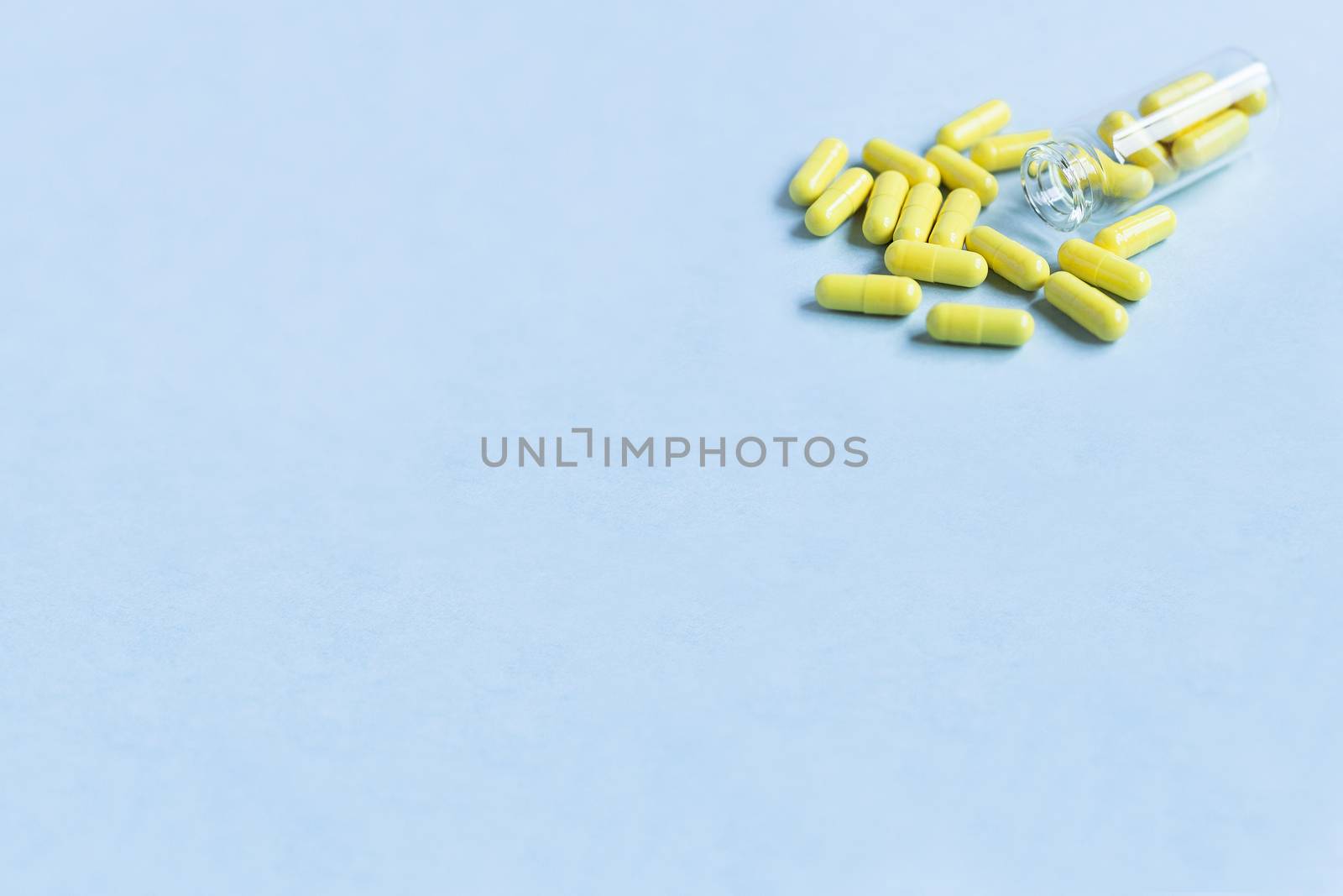 Yellow capsules are poured out of a bottle on a blue background. Omega-3 vitamins. food Supplement. Fish oil in capsules. Free space. space for text. copy space. blurred background. Selective focus.
