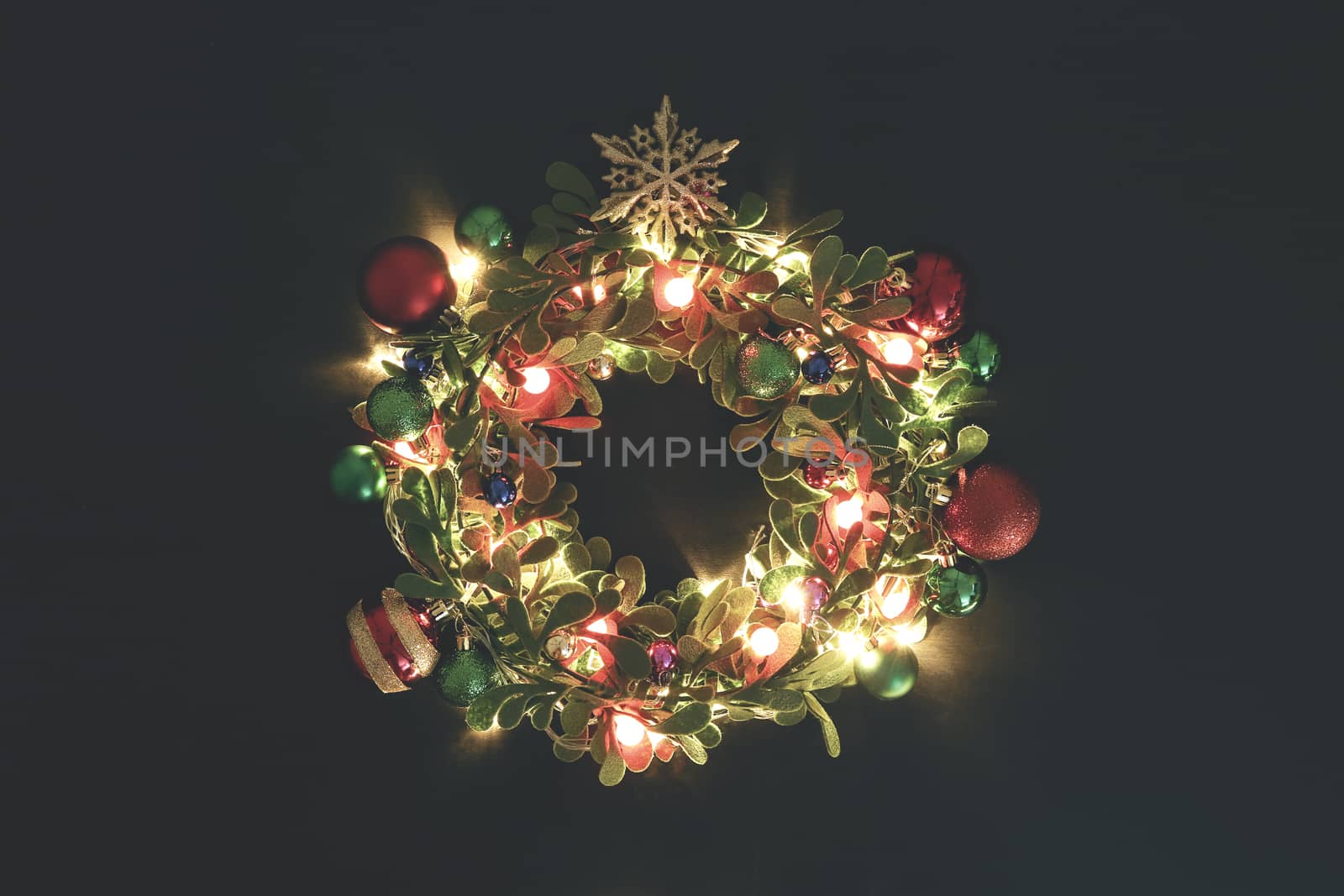 Greeting Season concept.Christmas wreath with decorative light on dark wood background