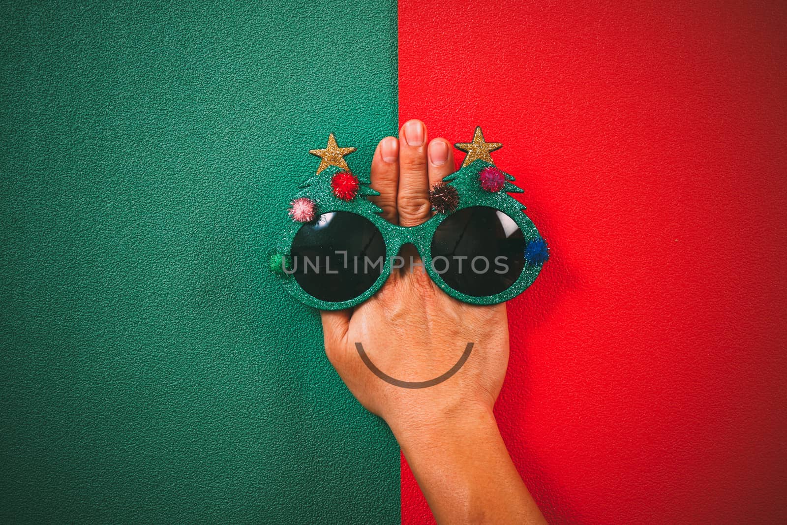 Christmas glasses that decoration with Christmas tree and red ball on hand on green and red  background