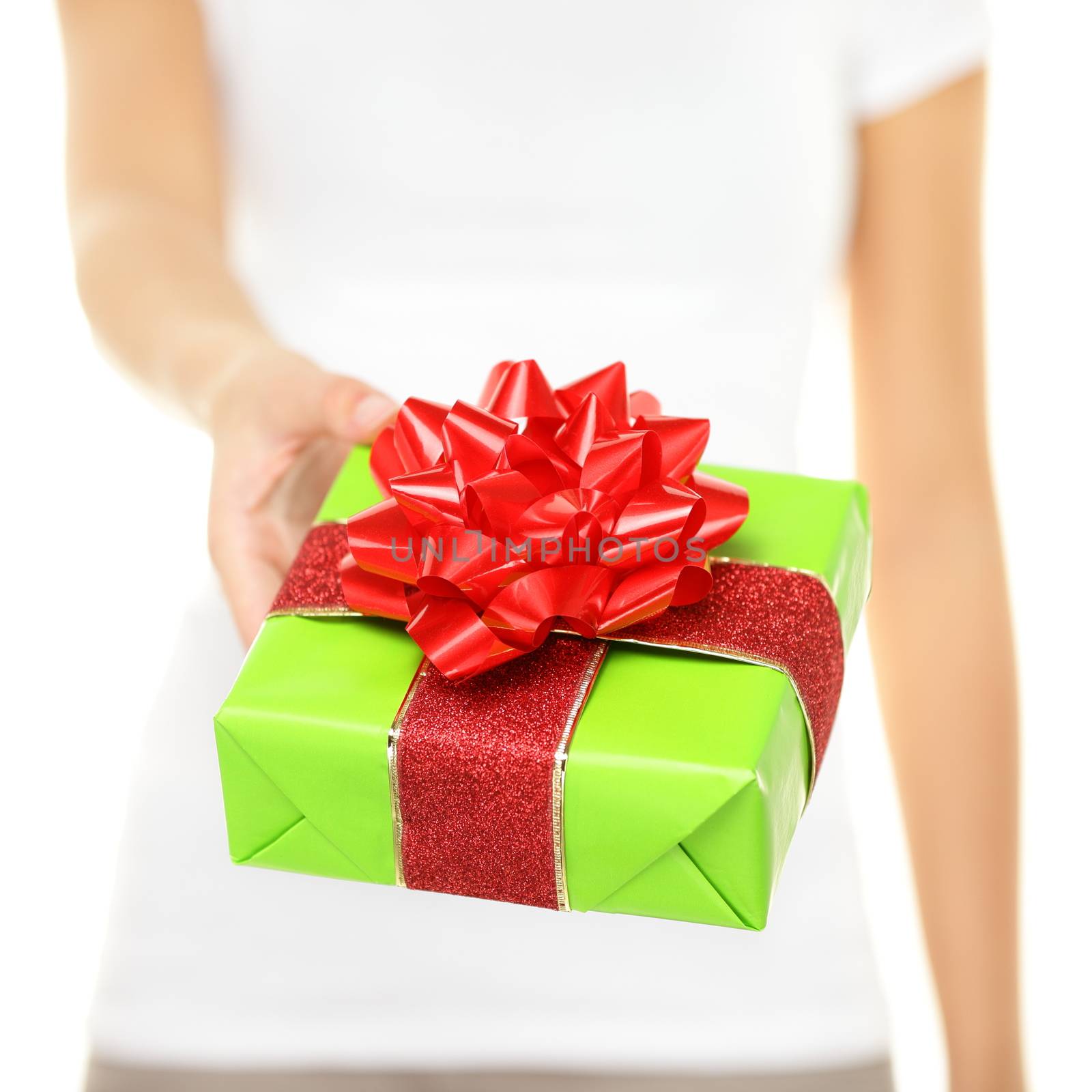 Woman holding gift. Closeup of female hands showing and giving gifts on white background. Green wrapping paper and big red ribbon