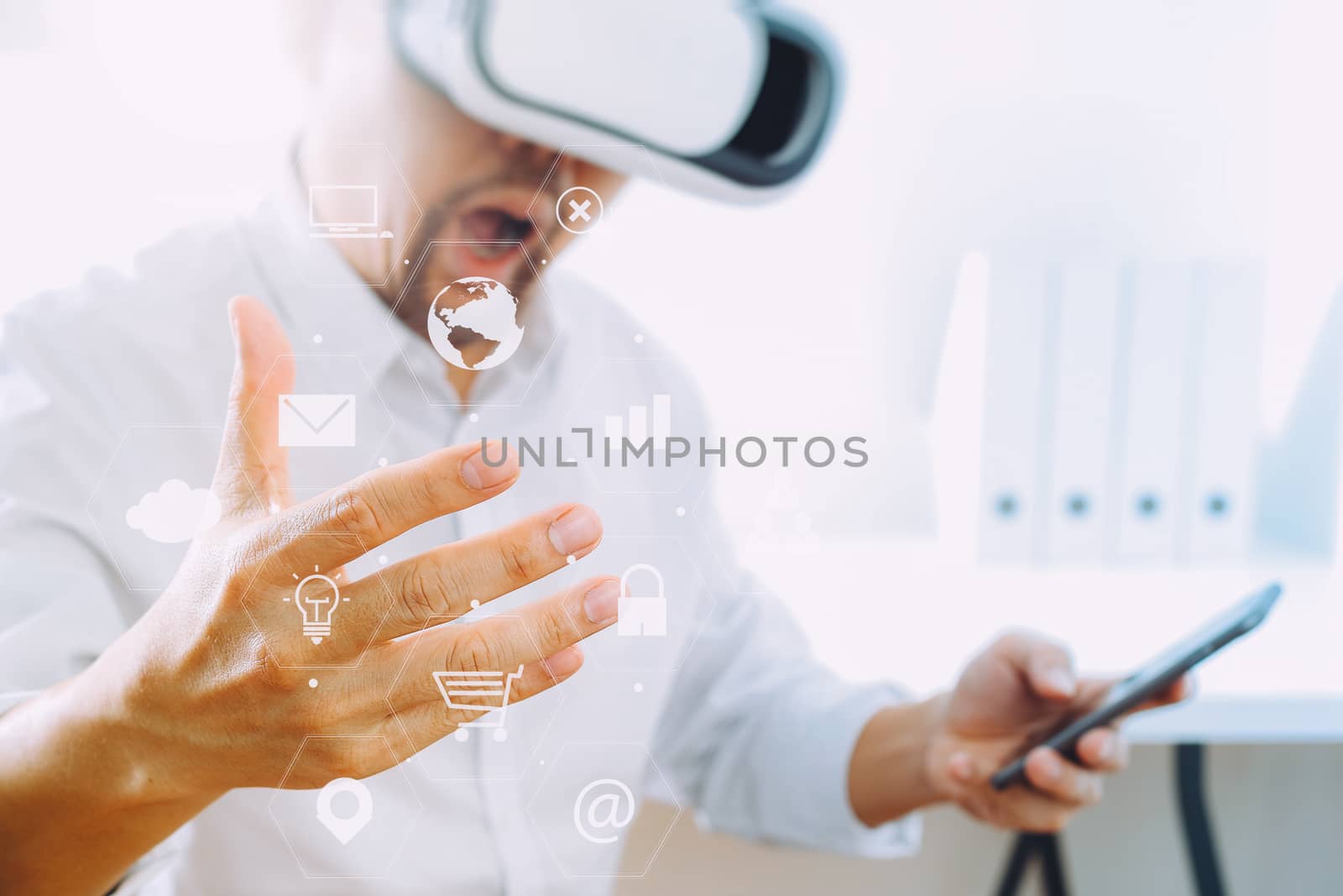 businessman wearing virtual reality goggles in modern office with mobile phone using with VR headset with screen icon diagram