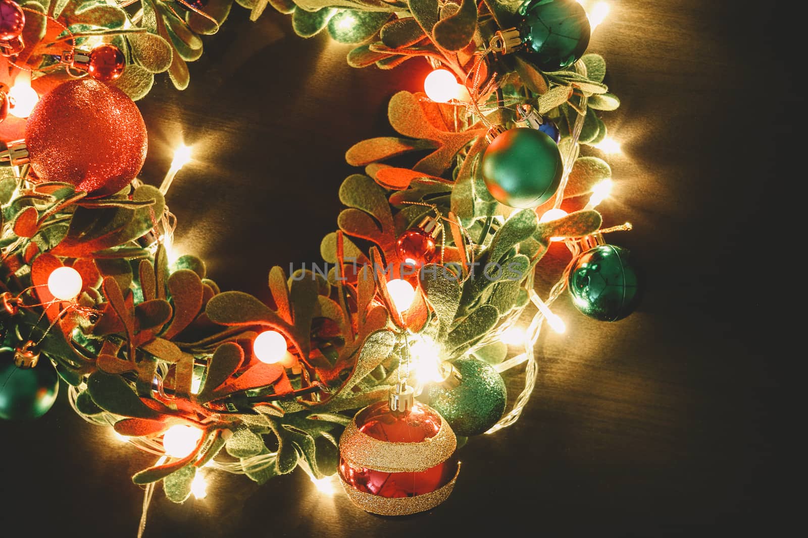 Greeting Season concept.Christmas wreath with decorative light on dark wood background