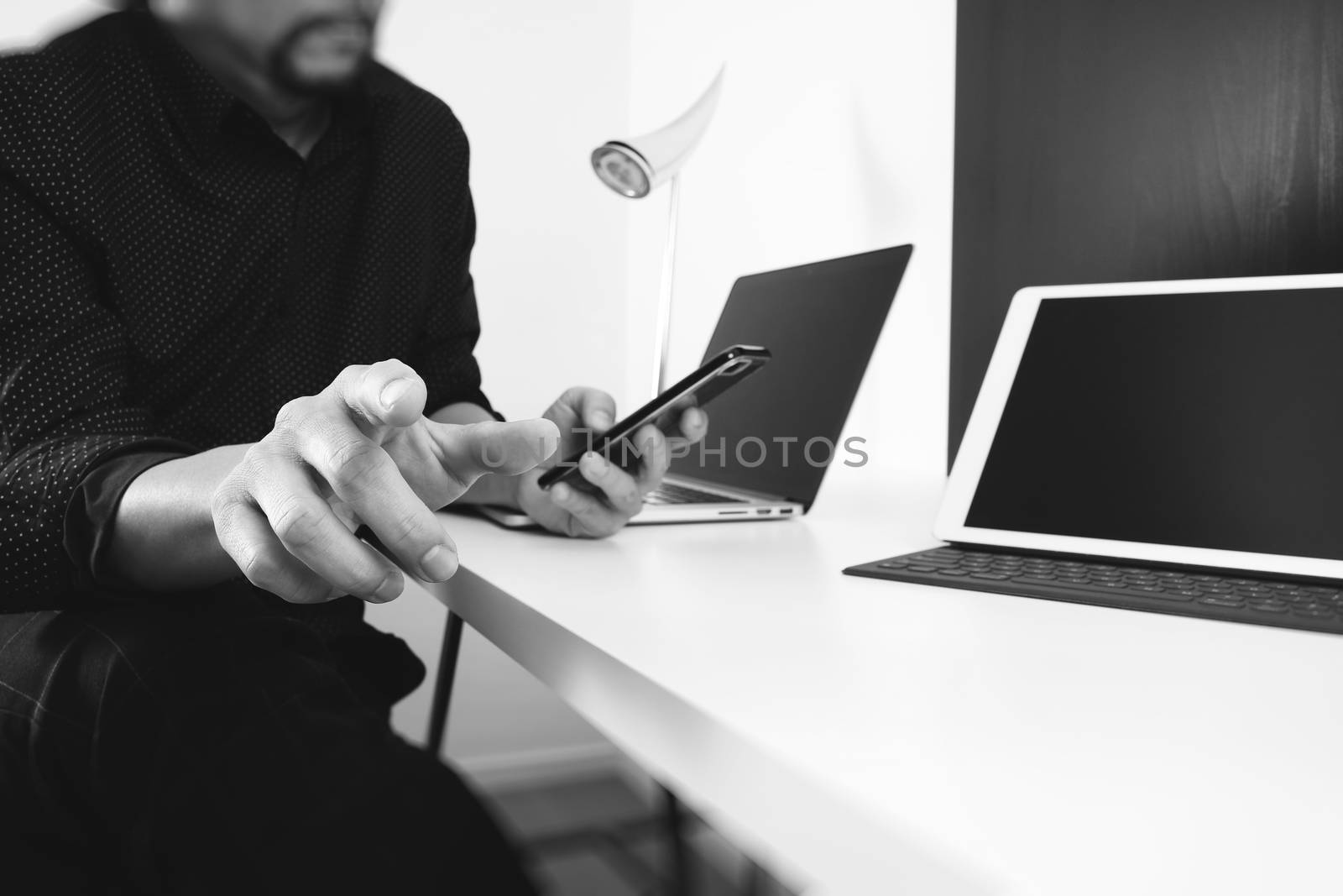 businessman working with smart phone and digital tablet and laptop computer in modern office ,black and white