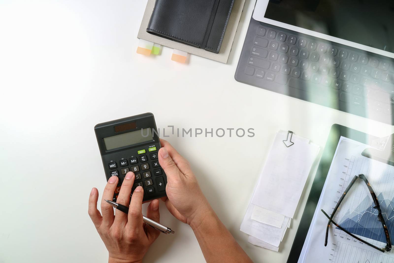 top view of businessman hand working with finances about cost and calculator and latop with mobile phone on withe desk in modern office 