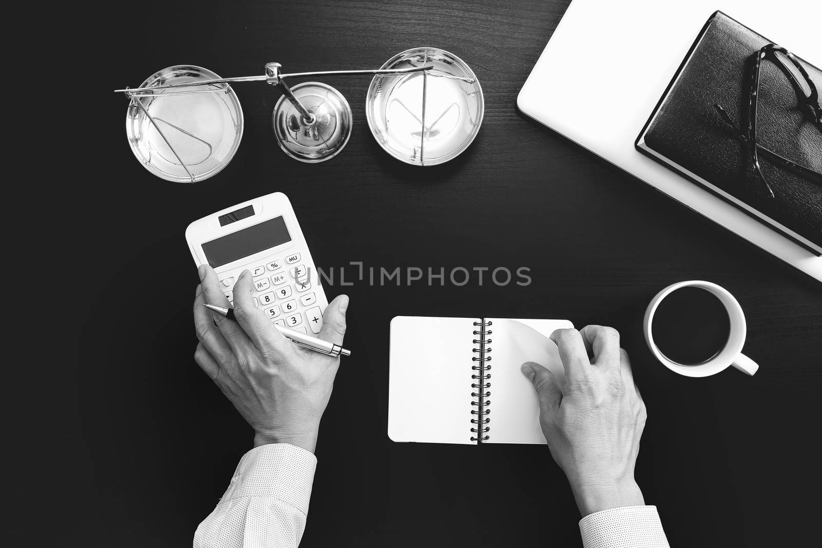 justice and law concept.businessman or lawyer or accountant working on accounts using a calculator and laptop computer and documents in modern office,black and white