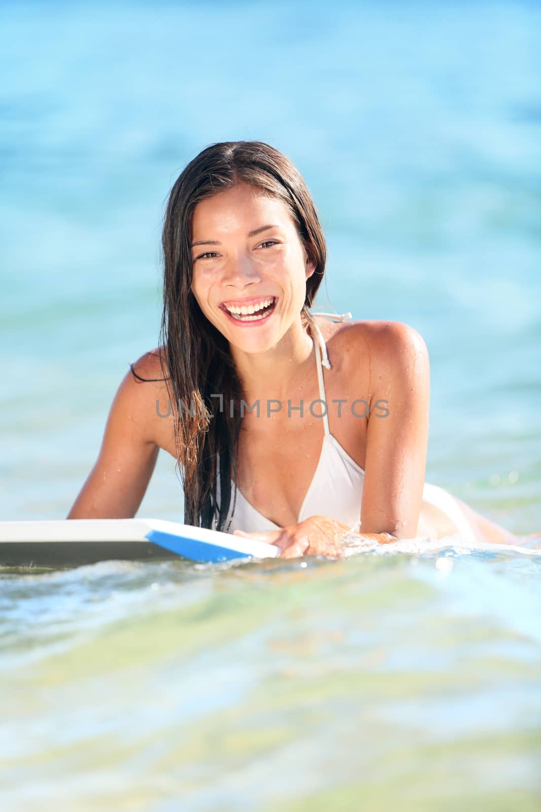 Surfboard happy smiling pretty mixed race young woman - enjoying vacation holiday surfing the ocean. Maui, Hawaii
