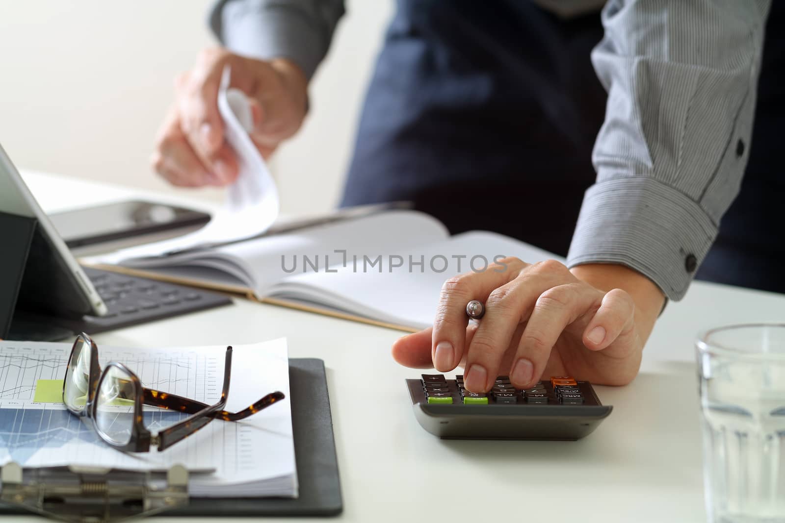 businessman hand working with finances about cost and calculator and latop with mobile phone on withe desk in modern office 