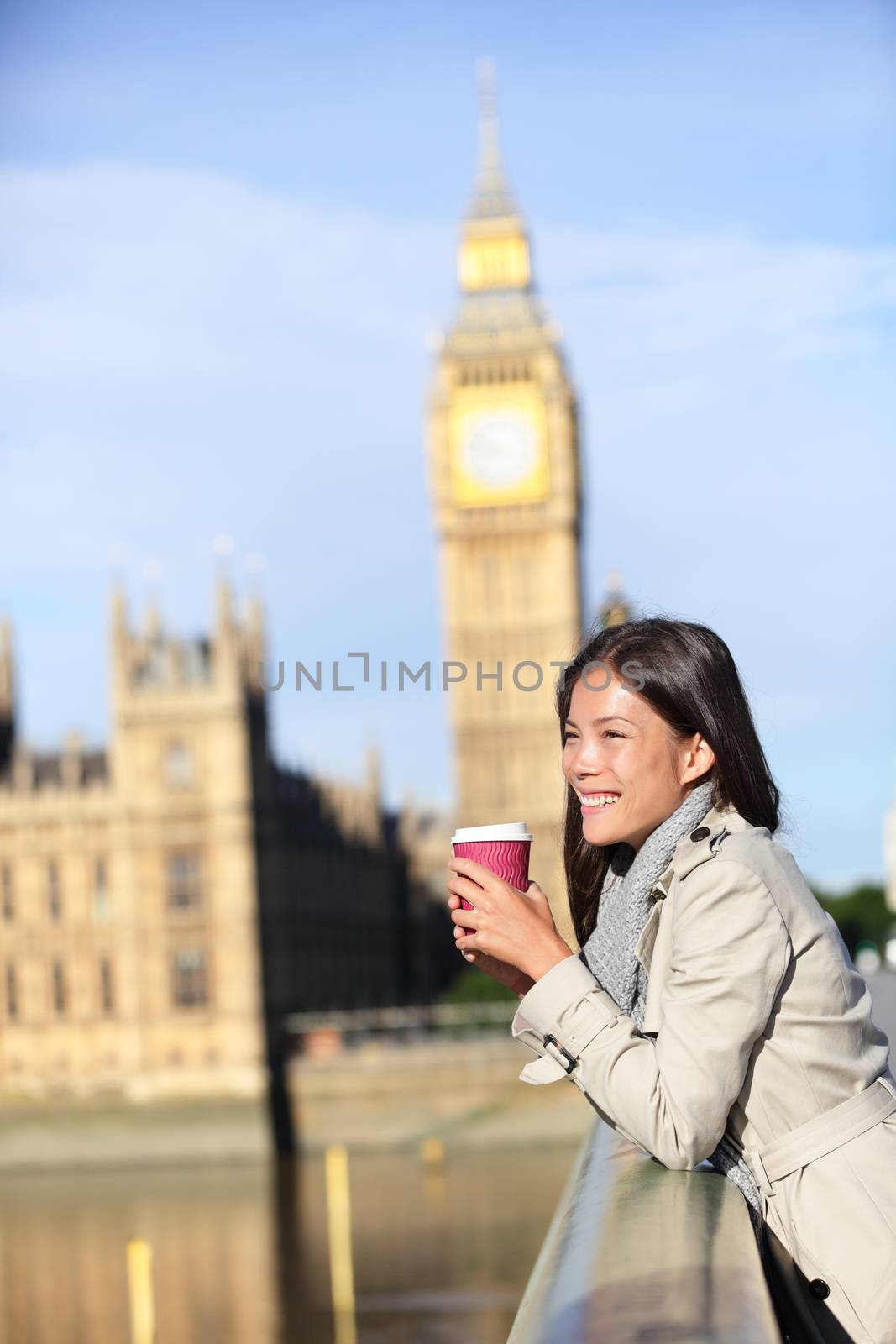 London woman drinking coffee happy by Big Ben laughing. Young female professional on Westminster Bridge, London, England. Beautiful young multiracial Asian Caucasian girl.