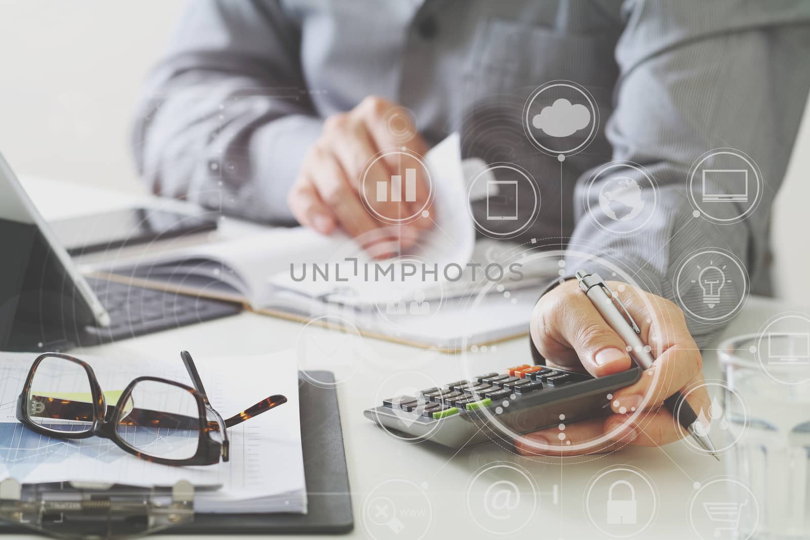 businessman hand working with finances about cost and calculator and latop with mobile phone on withe desk in modern office with VR icon diagram