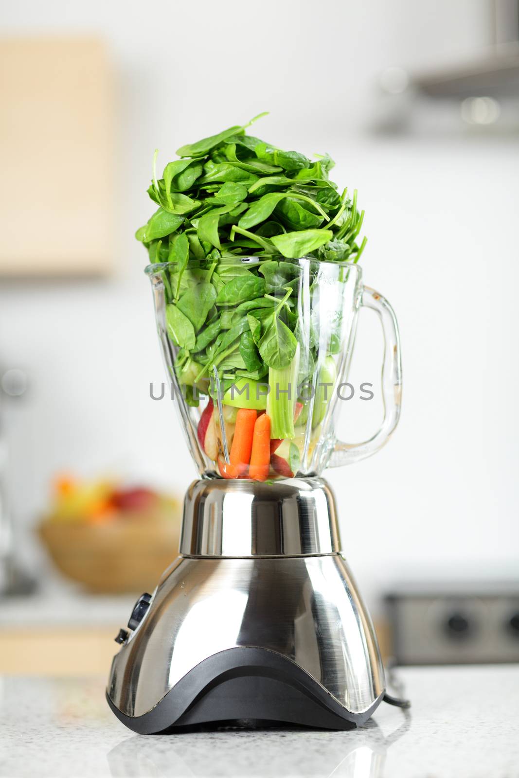 Green vegetable smoothie in blender. Healthy food concept with spinach, celery, carrot etc vegetables smoothies ready in blender in kitchen at home.