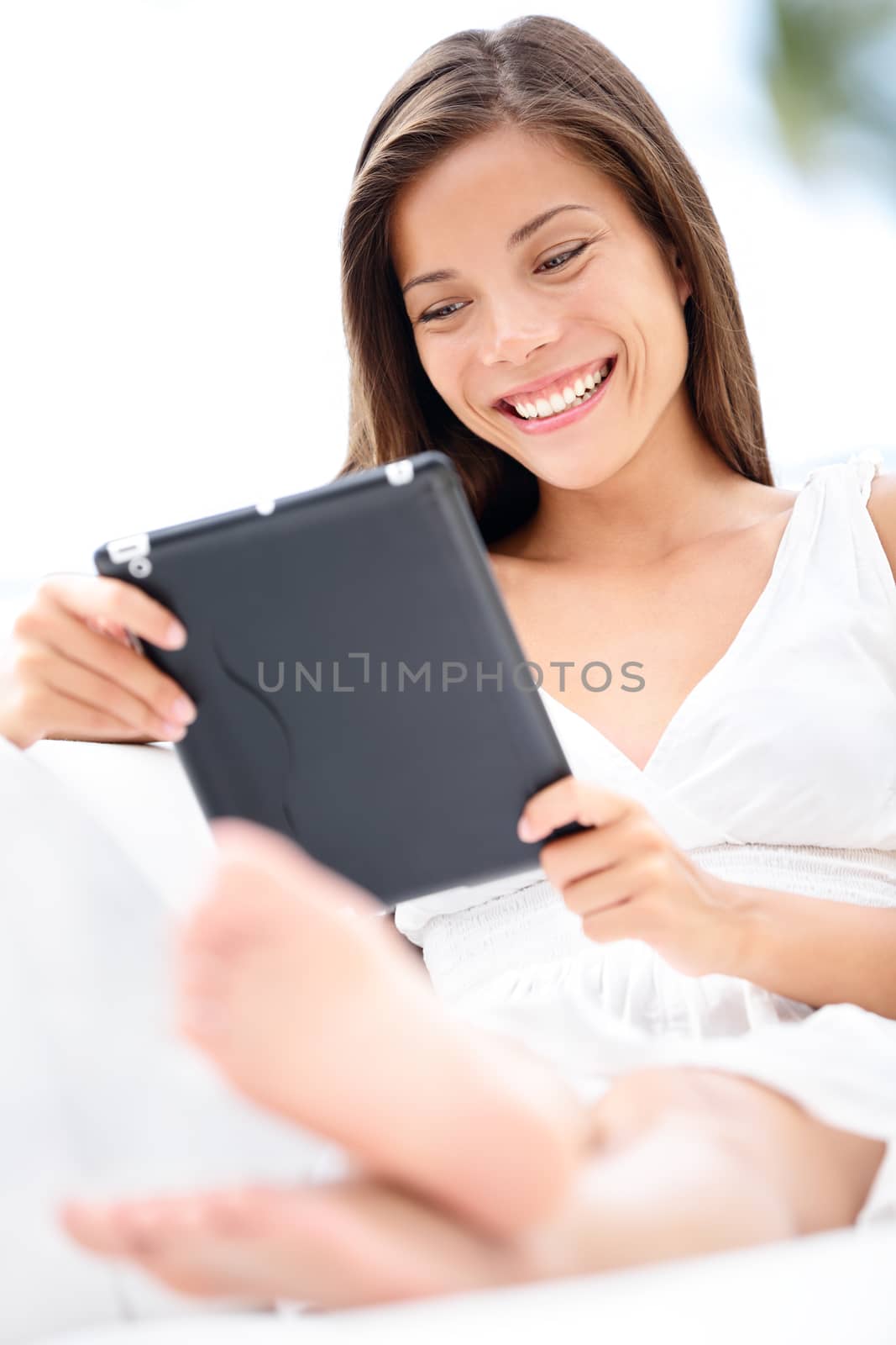 Tablet computer. Lifestyle with young caucasian asian mixed race woman model smiling using tablet pc in sofa at home outdoor in summer smiling happy.