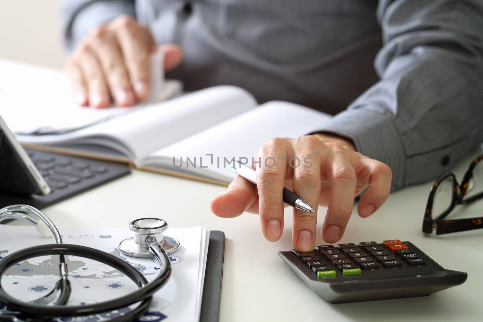 Healthcare costs and fees concept.Hand of smart doctor used a calculator for medical costs in modern hospital 