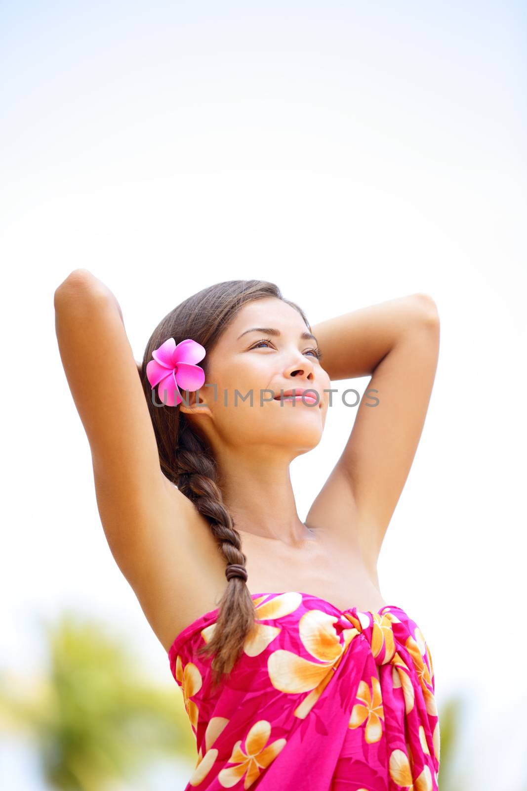 Spa ethnic mixed race pretty serene woman in sarong relaxed enjoying holiday - beach wellness on Hawaii in sun and warm, meditating arms up hands behind head