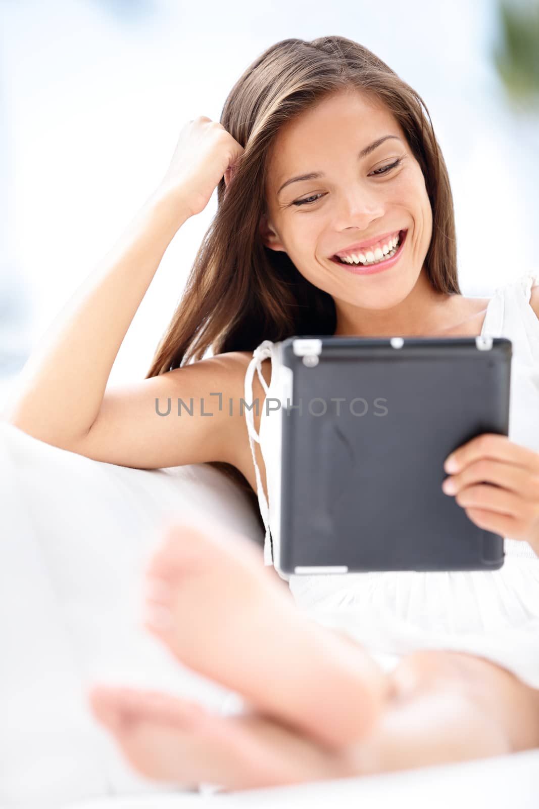 Tablet computer. Woman young smiling mixed race reading relaxed on black tablet