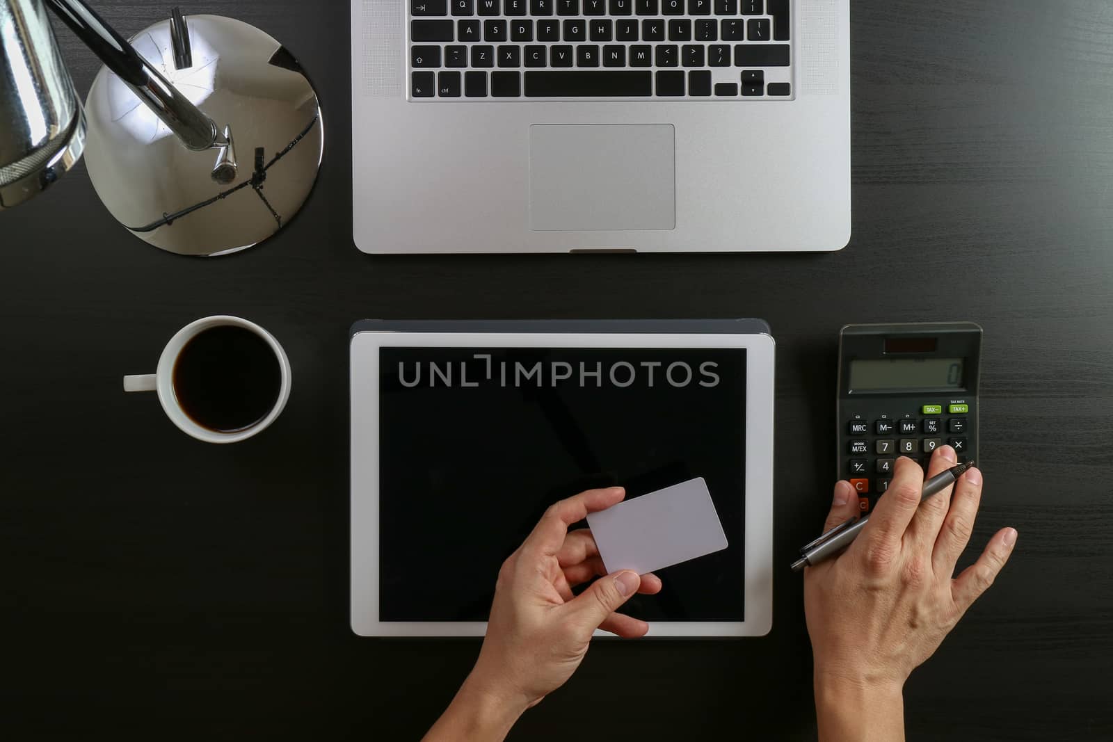 Internet shopping concept.Top view of hands working with calculator and laptop and credit card and tablet computer on dark wooden table background