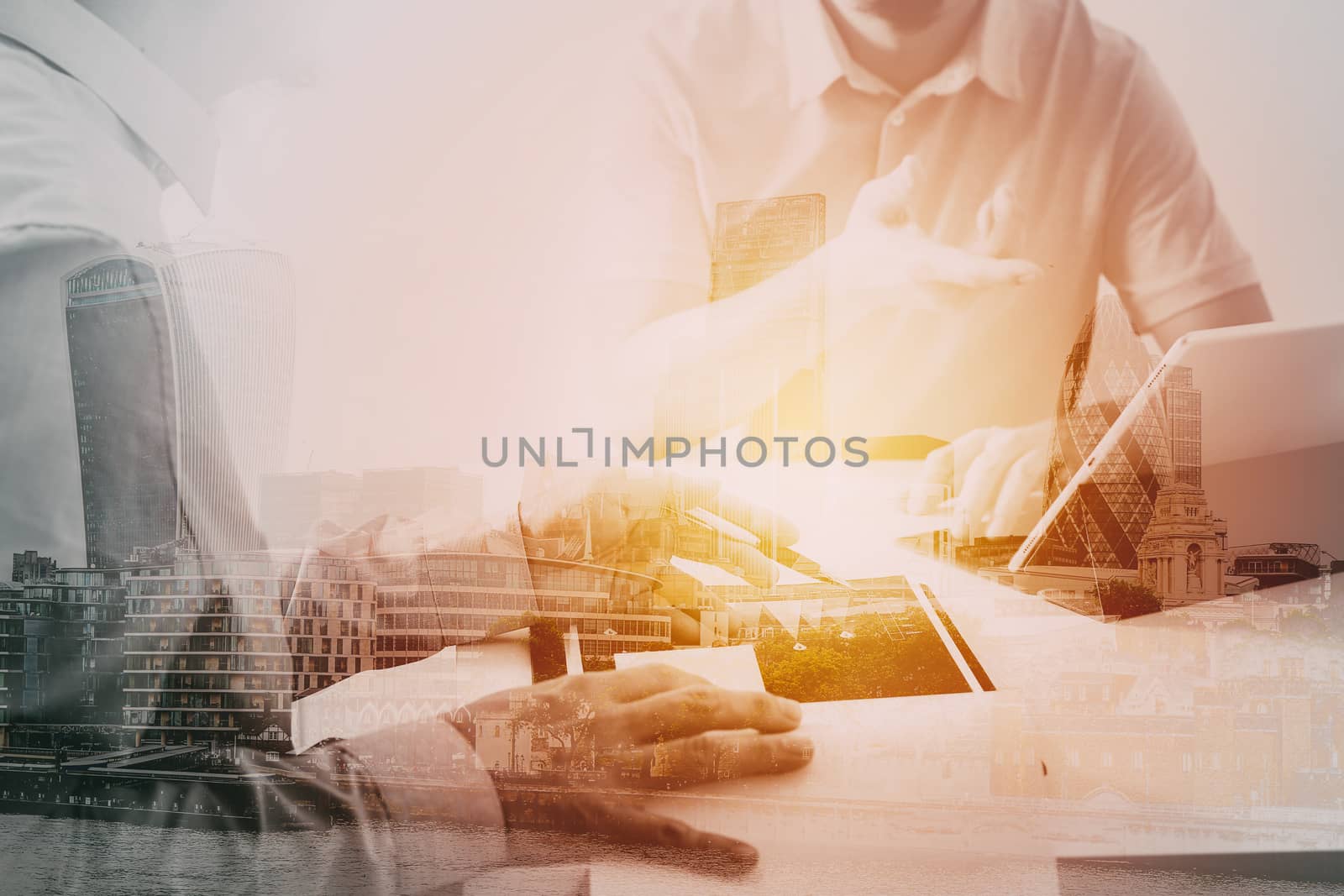 Businessmen working together on a document and using smart phone and digital tablet and laptop computer in modern office with city exposure                                                            