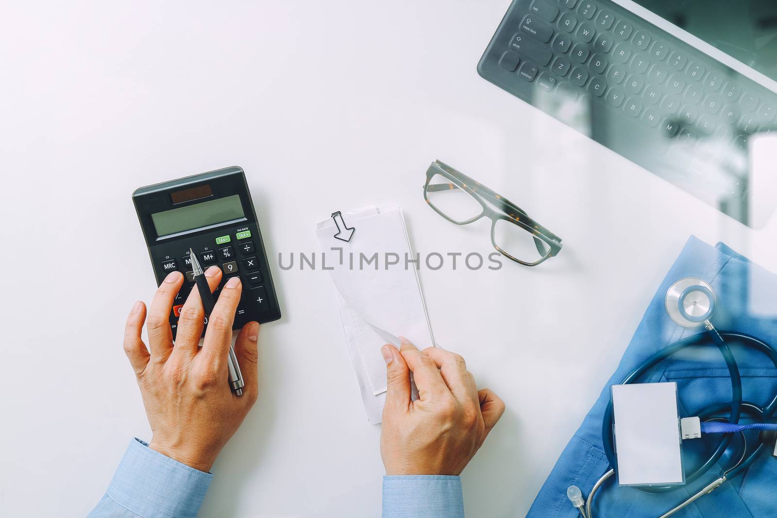 top view of Healthcare costs and fees concept.Hand of smart doctor used a calculator for medical costs in modern hospital 