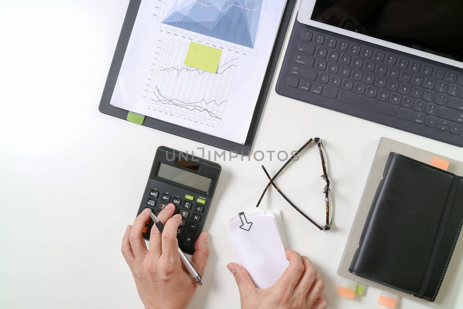 top view of businessman hand working with finances about cost and calculator and latop with mobile phone on withe desk in modern office 