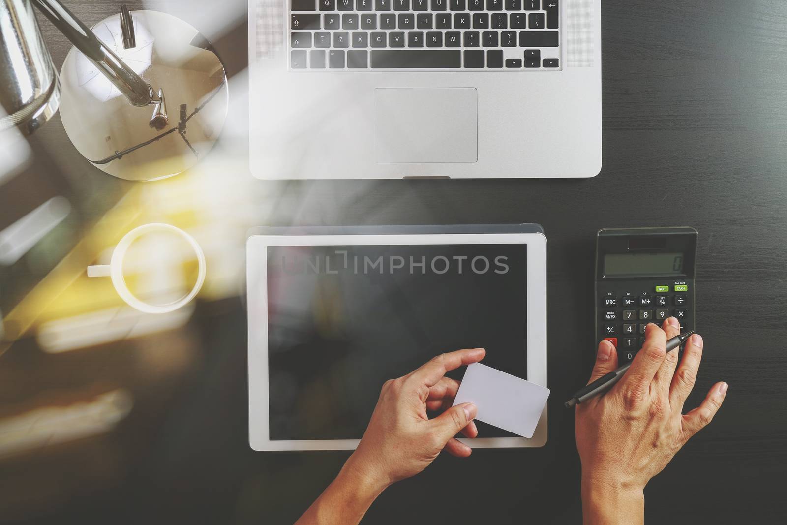 Internet shopping concept.Top view of hands working with calculator and laptop and credit card and tablet computer on dark wooden table background