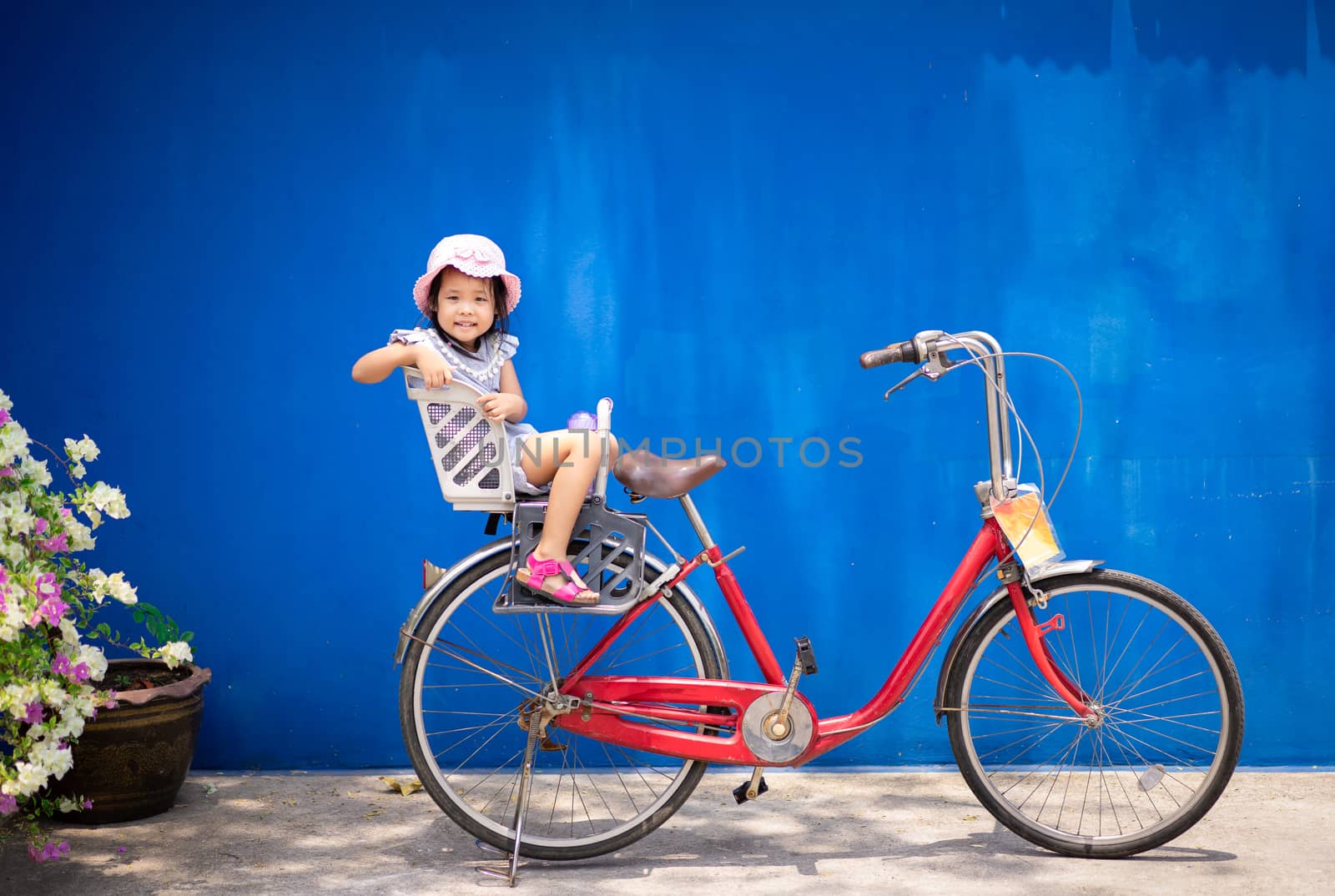 happy little girl ride a bicycle in the park with blue background