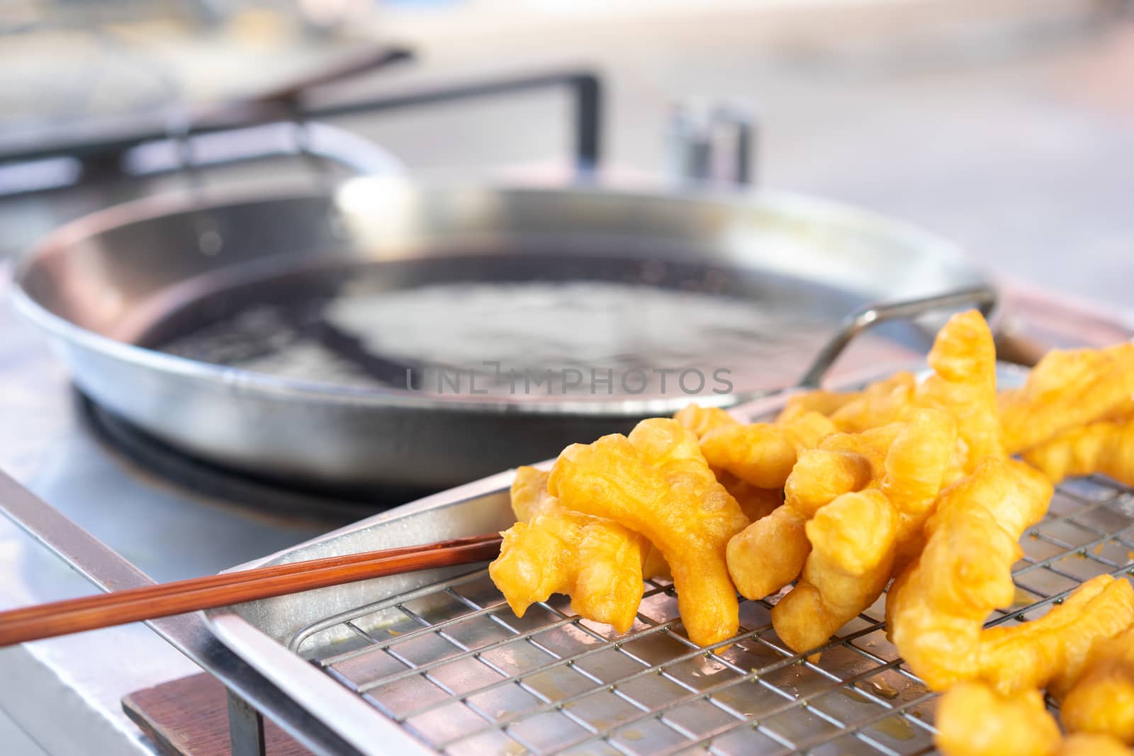 Deep fried dough sticks on steel net for sell with pan background