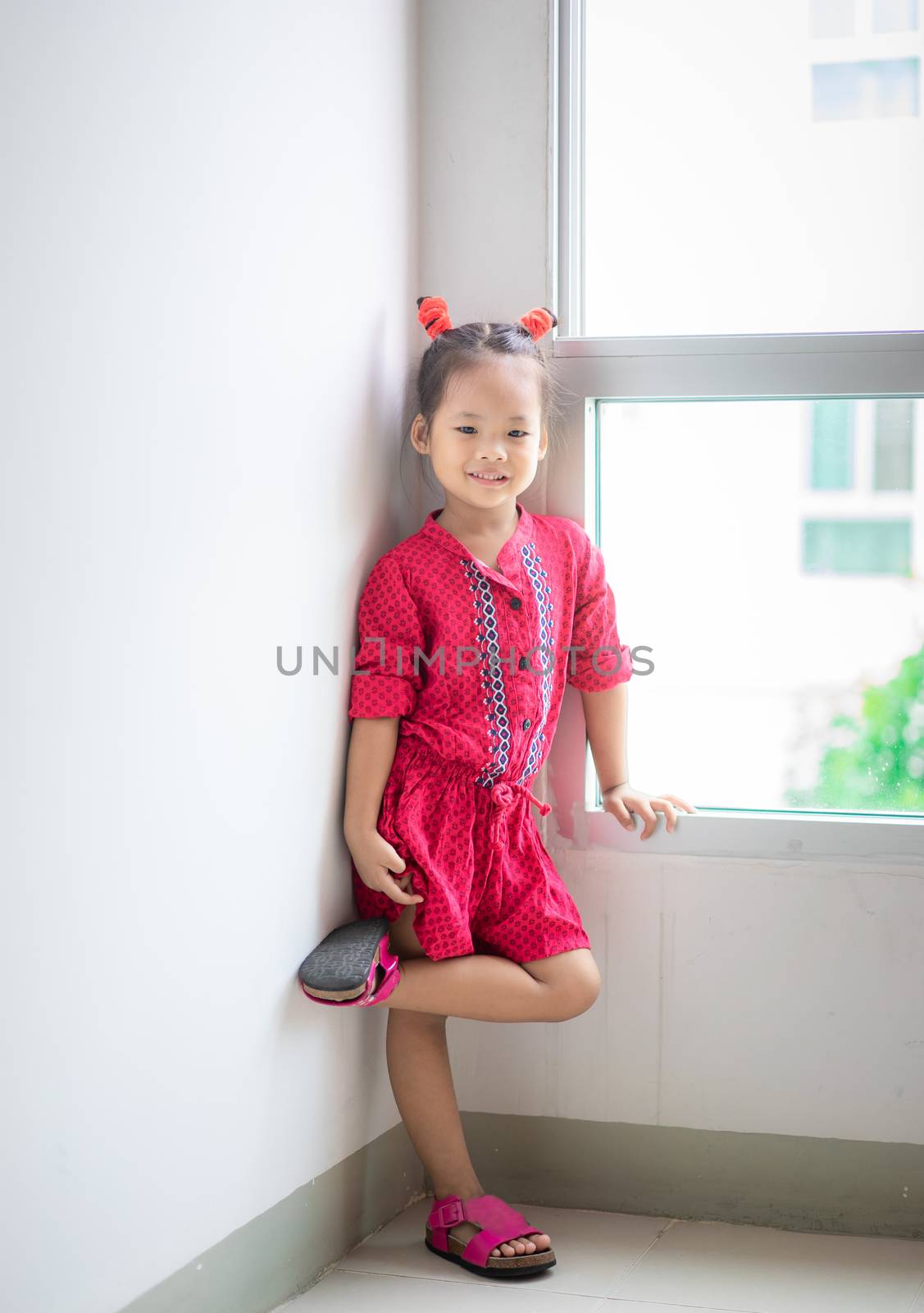 little girl in red dress standing and smile at home