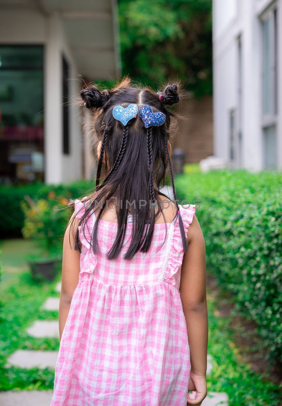 Back view of adorable little girl with beautiful hair walking in the park