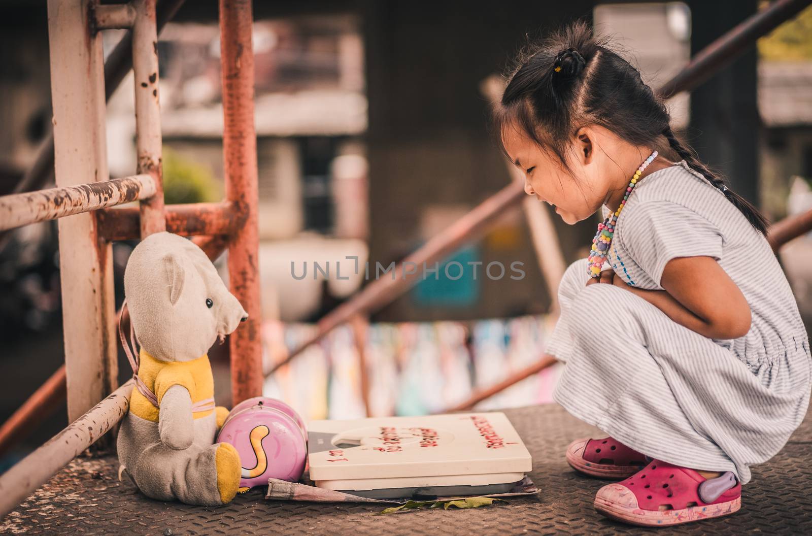 little girl talking to the doll on the bridge