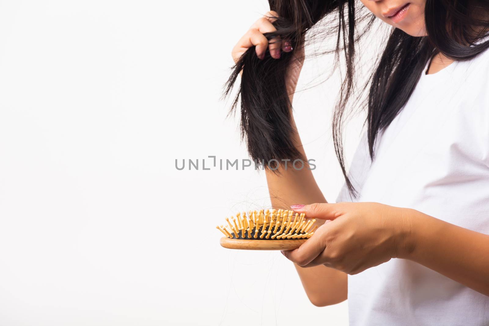 Asian woman unhappy weak hair her hold hairbrush with damaged long loss hair in the comb brush on hand and she looking to hair, studio shot isolated on white background, medicine health care concept